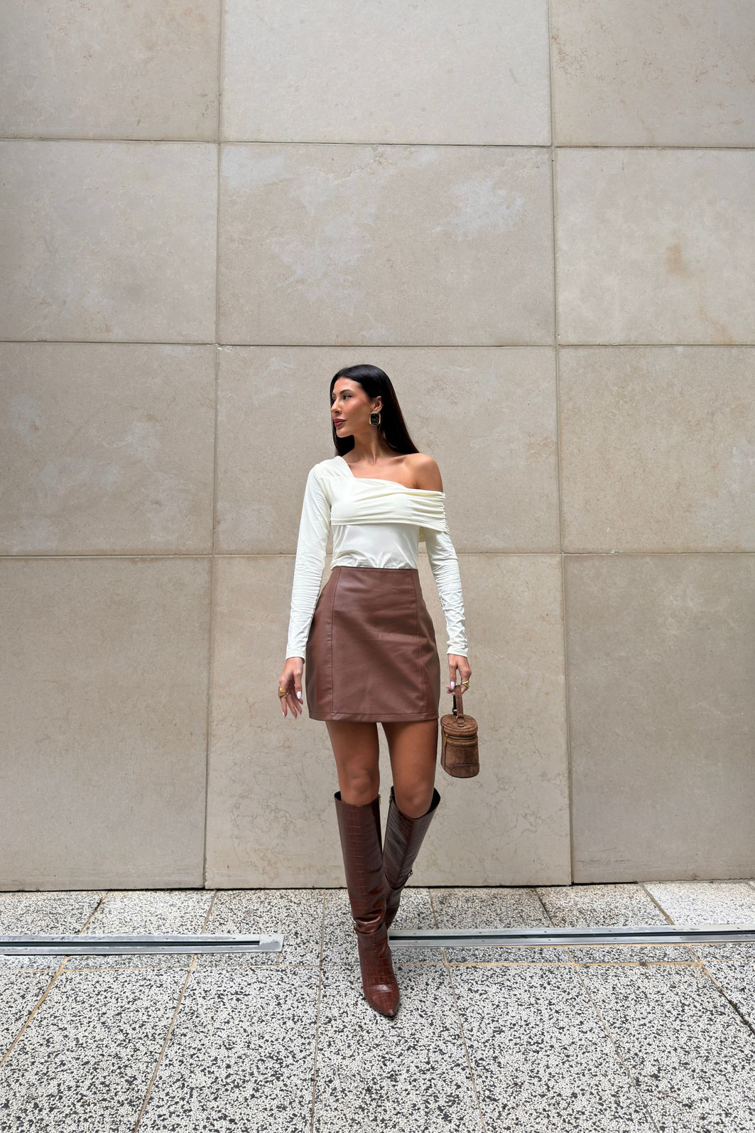 SAIA DE POLIUTERANO COM RECORTES DAYDREAM MARROM Saia feminina marrom em poliuretano com cintura alta e recortes verticais, modelagem ajustada e visual sofisticado tipo couro em look moderno com bota alta