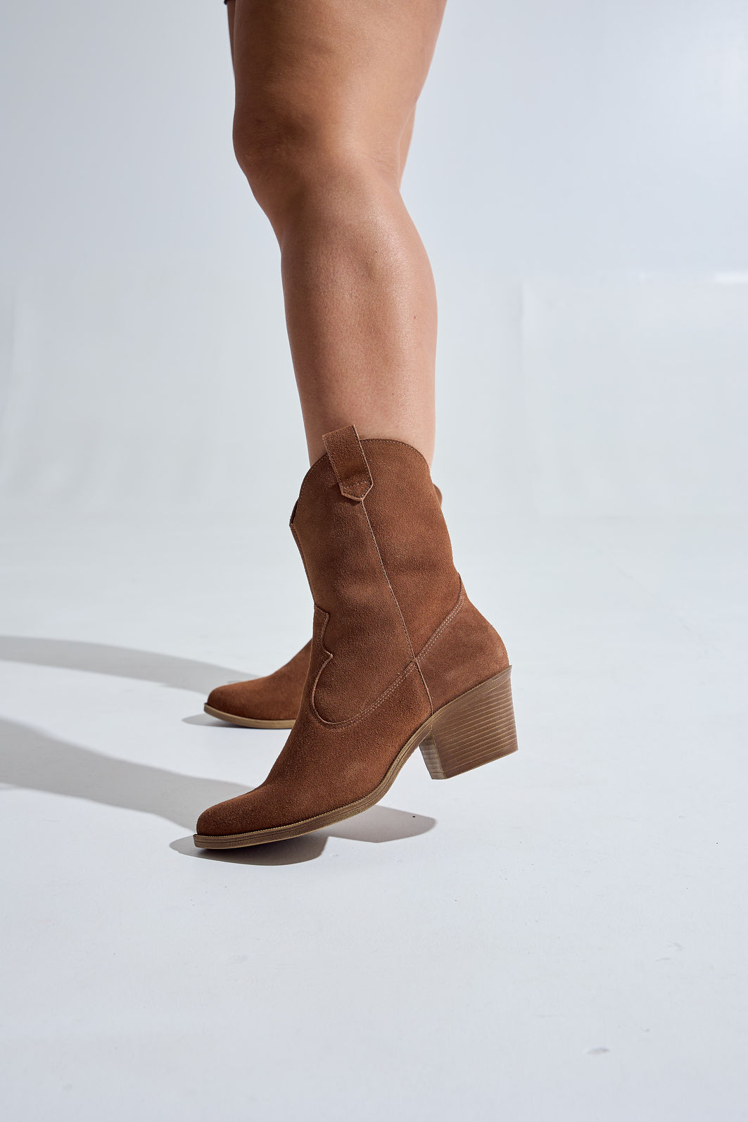bota-feminina-2-em-1-salto-baixo-couro-camel-zuri Pé feminino calçando bota 2 em 1 salto baixo couro camel Zuri sem o cano, versão curta