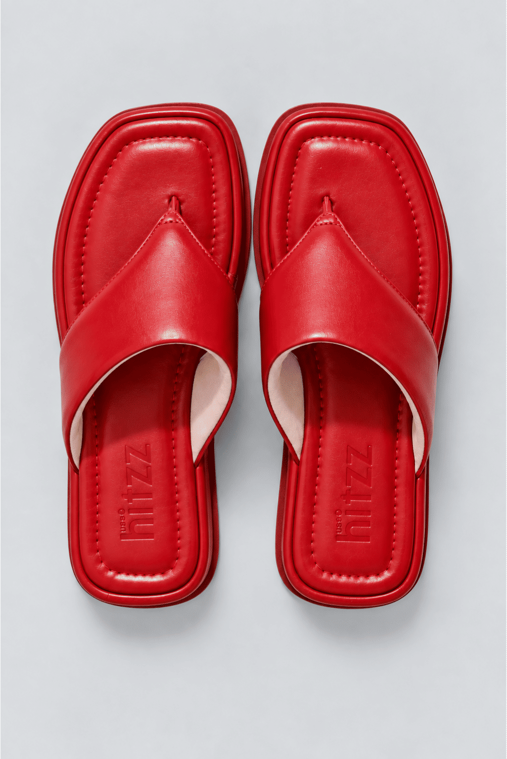 chinelo-flatform-couro-feminino-vermelho-buzios Par de chinelos flatform couro vermelho vistos de cima, palmilha com a marca hitzz gravada, fundo claro.