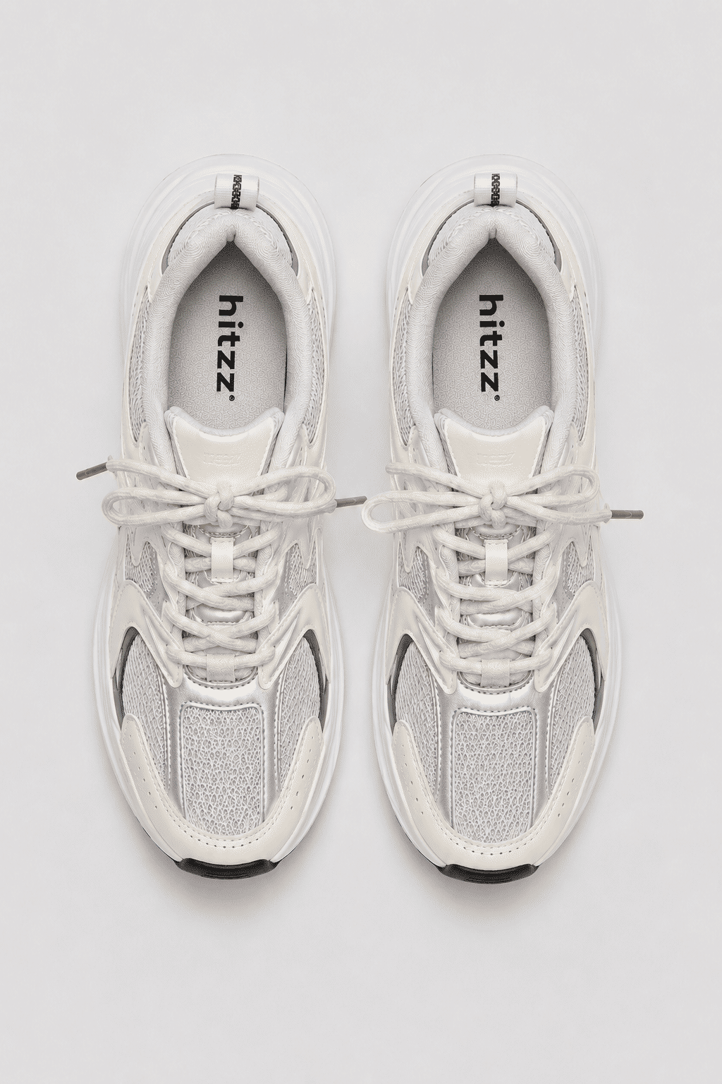Vista superior do Tênis Victoria Off White Par de Tênis Feminino Victoria Off White visto de cima, com detalhes prateados, recortes em tela, cadarços claros e palmilha com logo Hitzz.