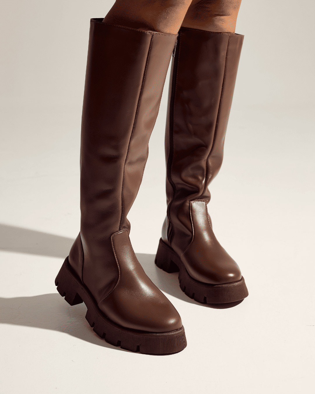 zuna-bota-feminina-cano-longo-tratorada-marrom Detalhe das pernas com bota feminina cano longo tratorada marrom ZUNA