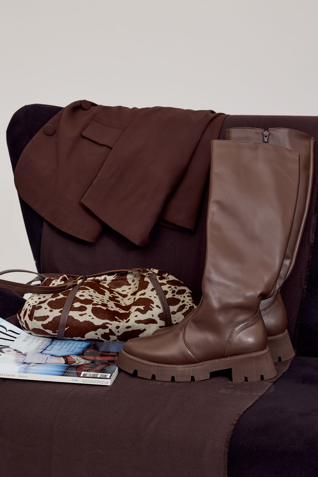 zuna-bota-feminina-cano-longo-tratorada-marrom Detalhe da bota feminina cano longo tratorada marrom ZUNA com casaco e bolsa animal print