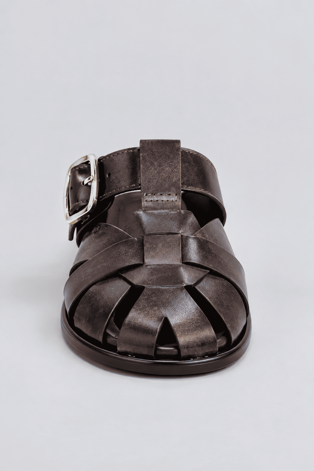 clog-feminino-fivela-marrom-aura Close frontal do clog marrom, mostrando as tiras entrelaçadas no bico e a fivela dourada.