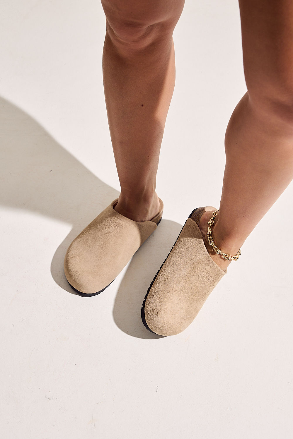 clog-feminino-anatomico-couro-camurca-bege-lina Mulher em pé calçando par de clogs anatômicos couro camurça bege Lina
