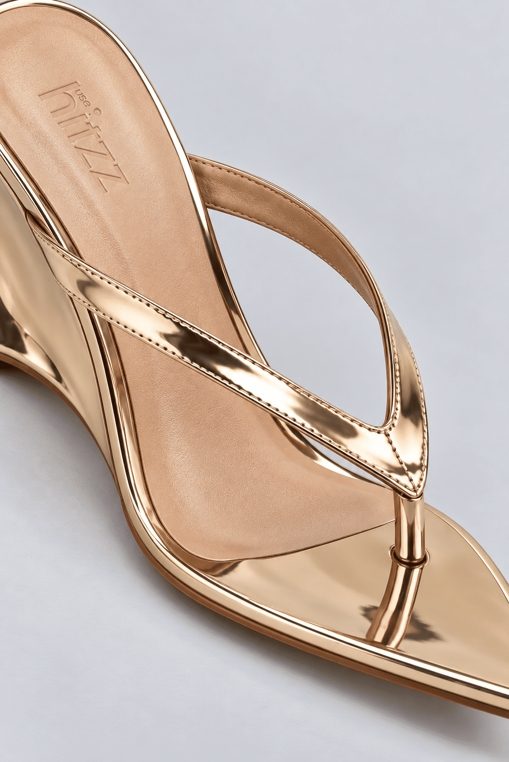 tamanco-feminino-dedo-salto-anabela-bico-folha-ouro-light-liz Close do tamanco dedo dourado metalizado, destacando a tira flip flop e o bico folha em detalhe.