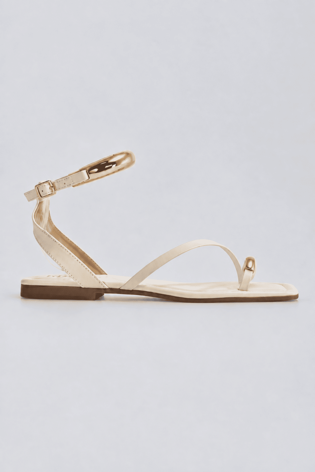 sandalia-rasteira-feminina-de-dedo-off-white-nati Sandália rasteira feminina de dedo off white com tira no tornozelo e detalhes dourados, vista lateral em fundo cinza claro.