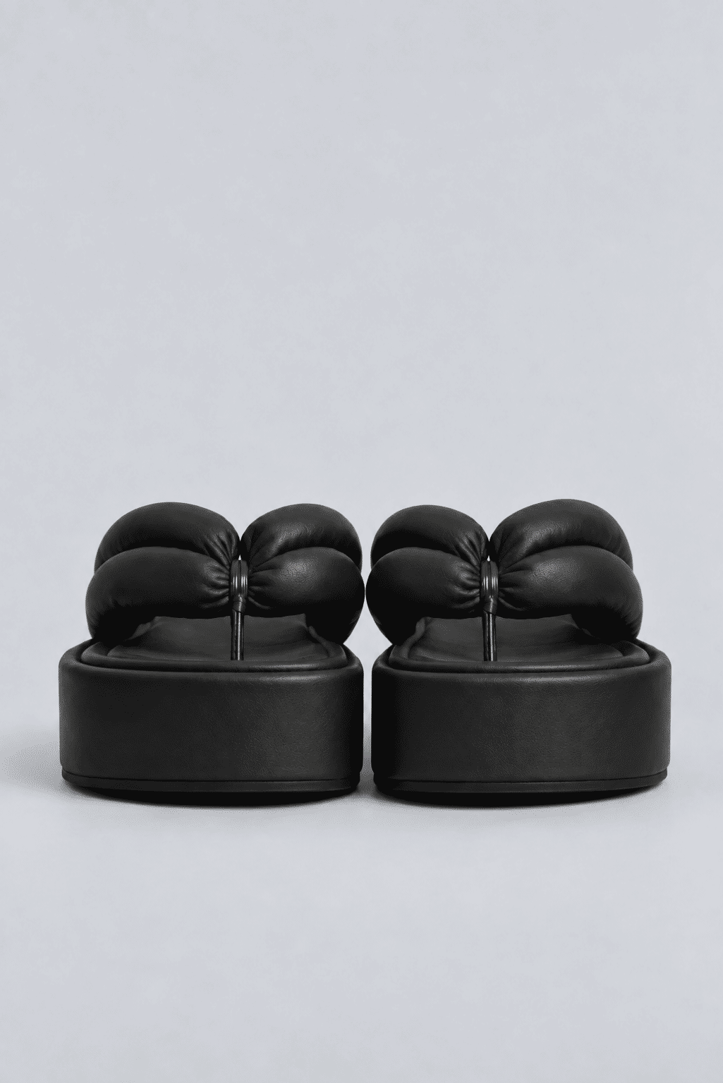 chinelo-flatform-tiras-puffer-preto-sakura Par do Chinelo Flatform Tiras Puffer Preto - Sakura visto de frente, destacando as tiras acolchoadas e a plataforma flatform