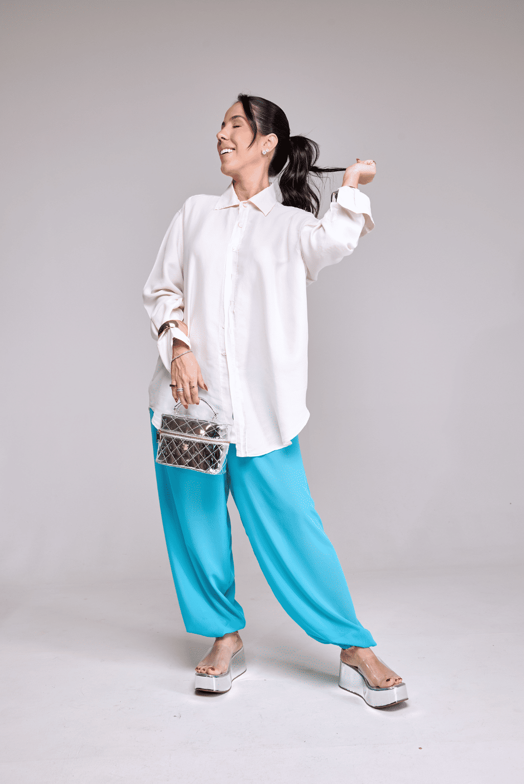 tamanco-flatform-feminino-tira-vinil-prata Modelo usando camisa branca e calça azul com o Adele - Tamanco Flatform Feminina Tira Vinil Prata, corpo inteiro