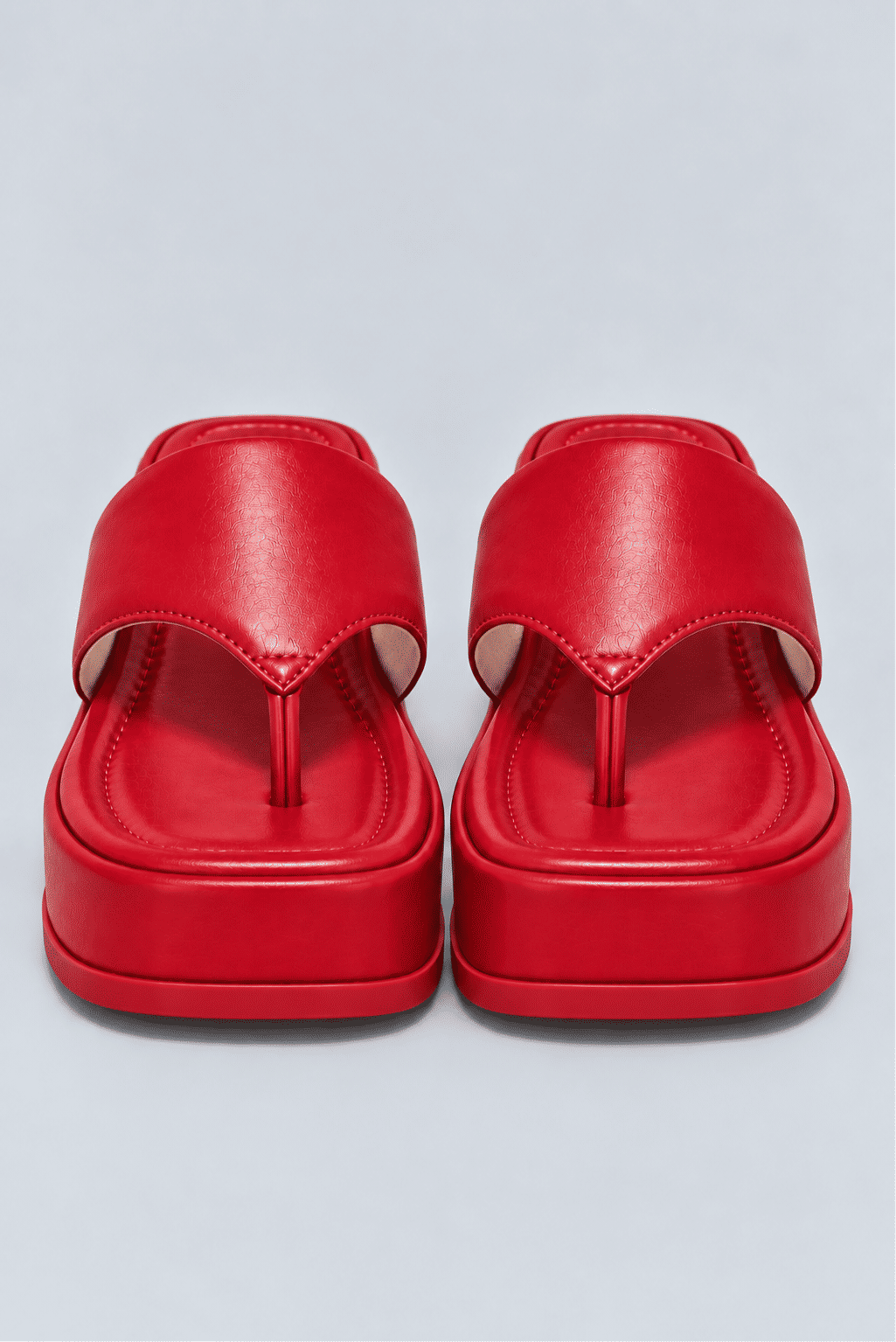 chinelo-flatform-couro-feminino-vermelho-buzios Par de chinelos flatform vermelho vistos de frente, mostrando a tira entre os dedos e o solado.