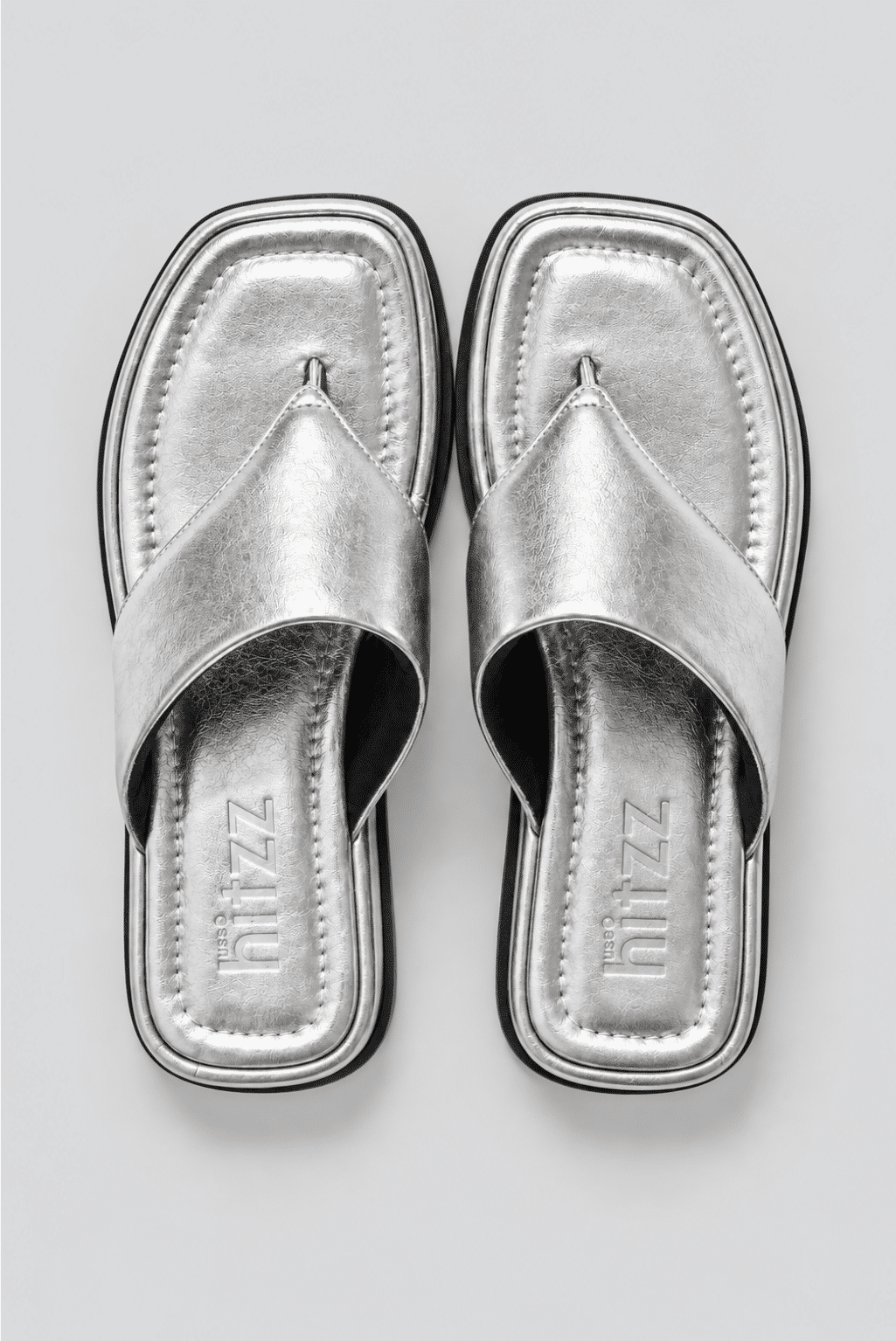 chinelo-flatform-feminino-prata-buzios Par de chinelos flatform prata vistos de cima, palmilha com a marca hitzz gravada, fundo claro.