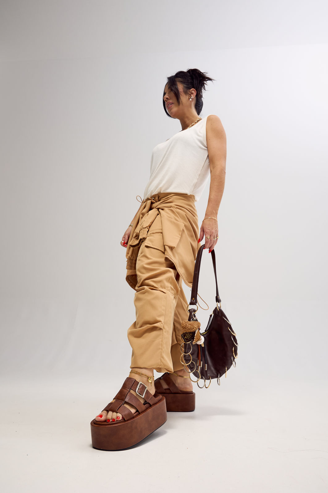 bangkok-tamanco-feminino-camel Modelo em pé com o Tamanco bangkok e bolsa Kuromi preta