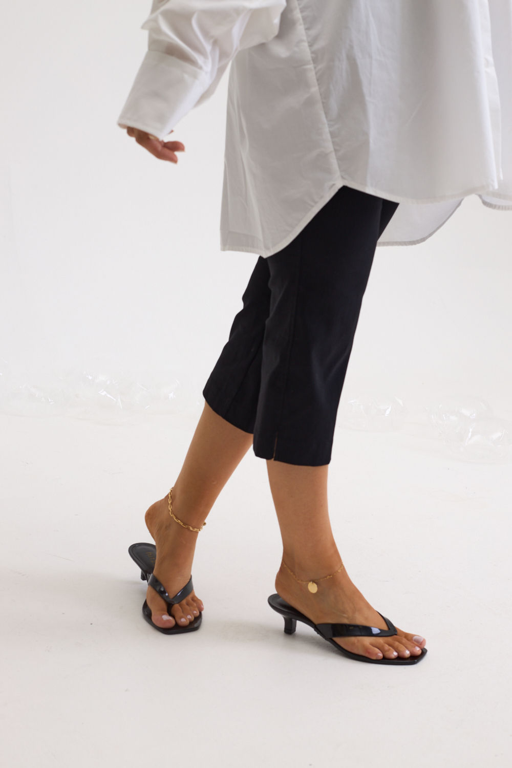 gummy-tamanco-feminino-salto-baixo-translucido-preto Tamanco Feminino Flip Flop Gummy preto em PVC translúcido nos pés da modelo caminhando, vista dos dois calçados