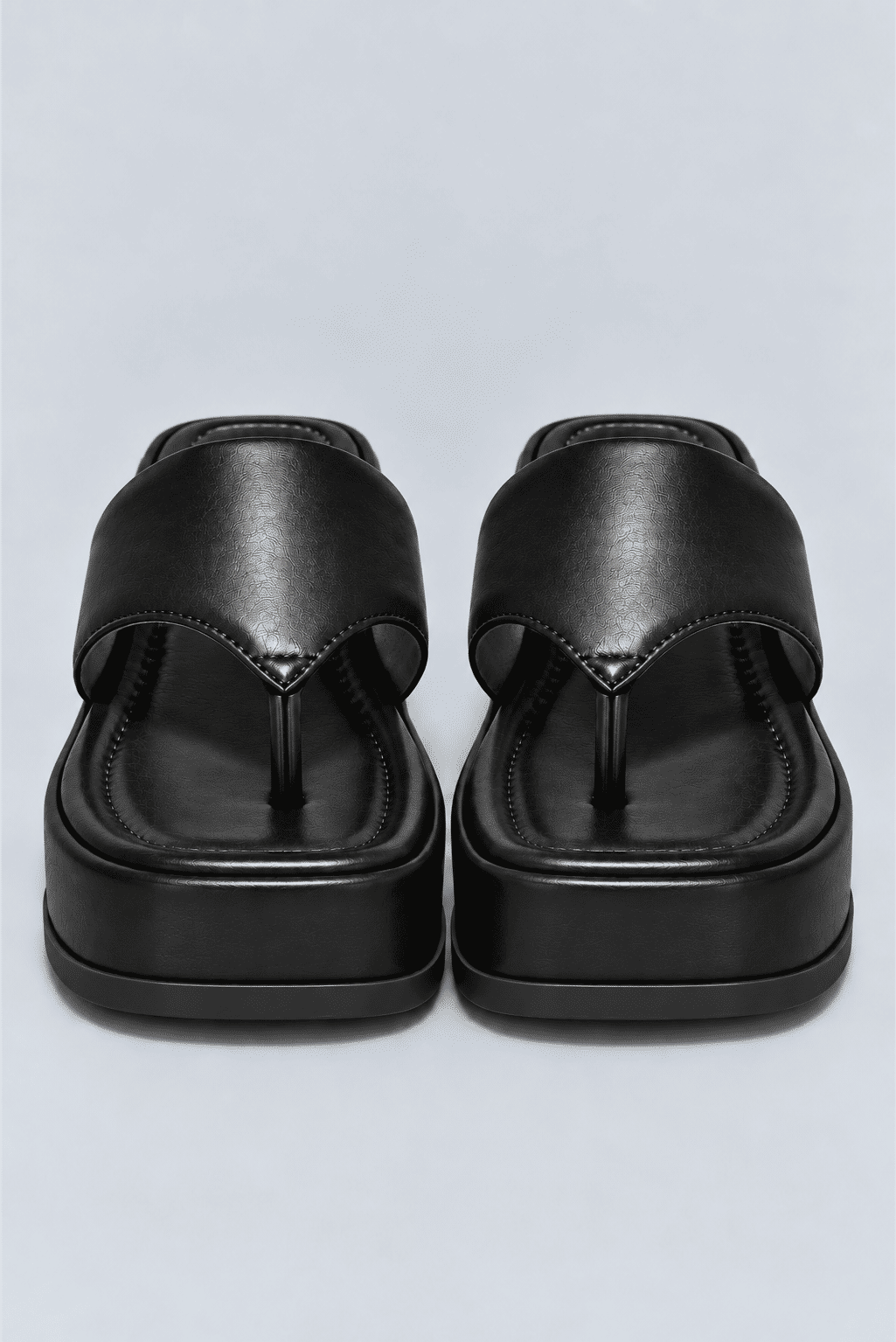 chinelo-flatform-couro-feminino-preto-buzios Par de chinelos flatform couro preto vistos de frente, mostrando a tira entre os dedos e o solado.