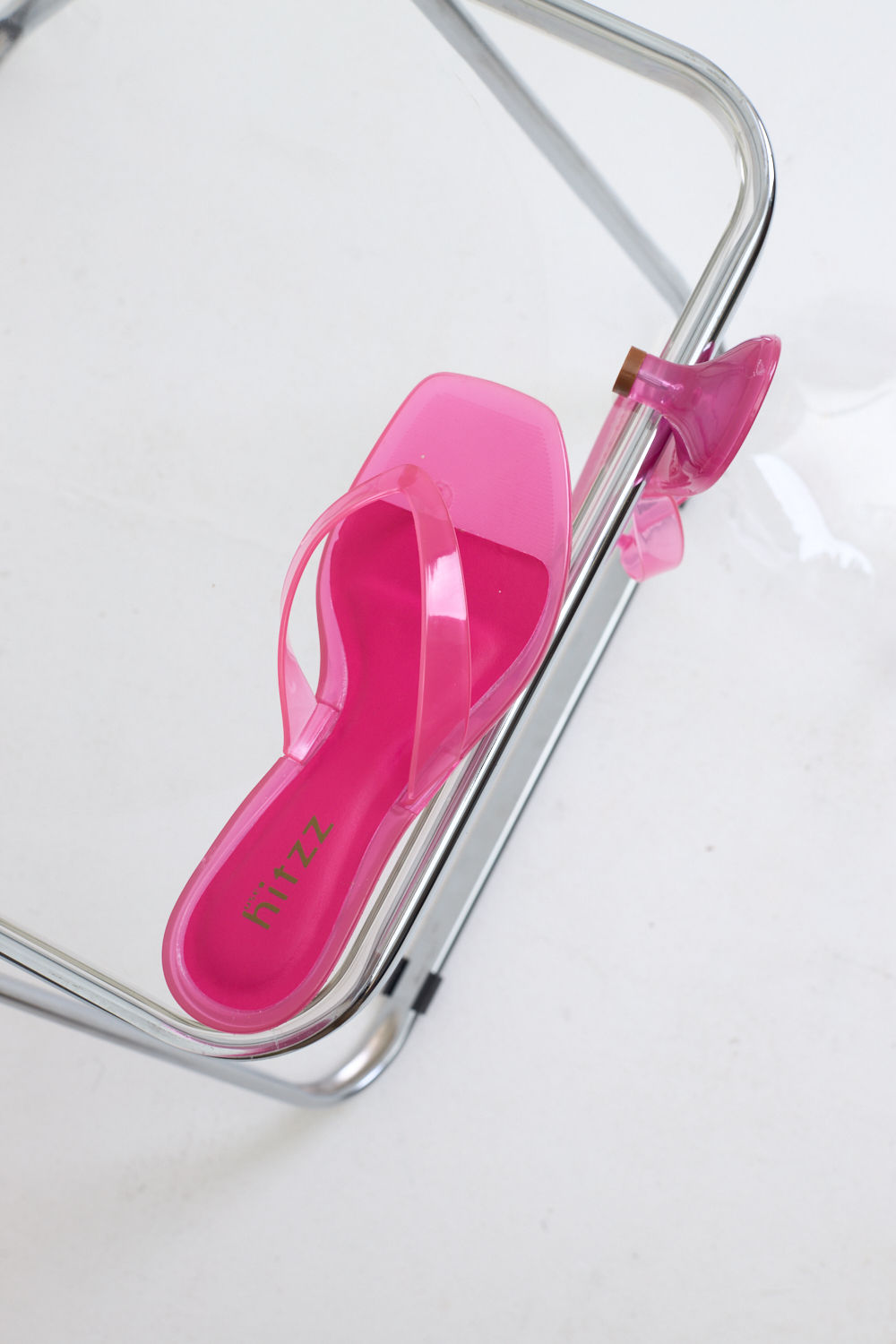 gummy-tamanco-feminino-translucido-rosa Par de Tamanco Feminino Flip Flop Gummy rosa em PVC translúcido sobre cadeira transparente, vista superior