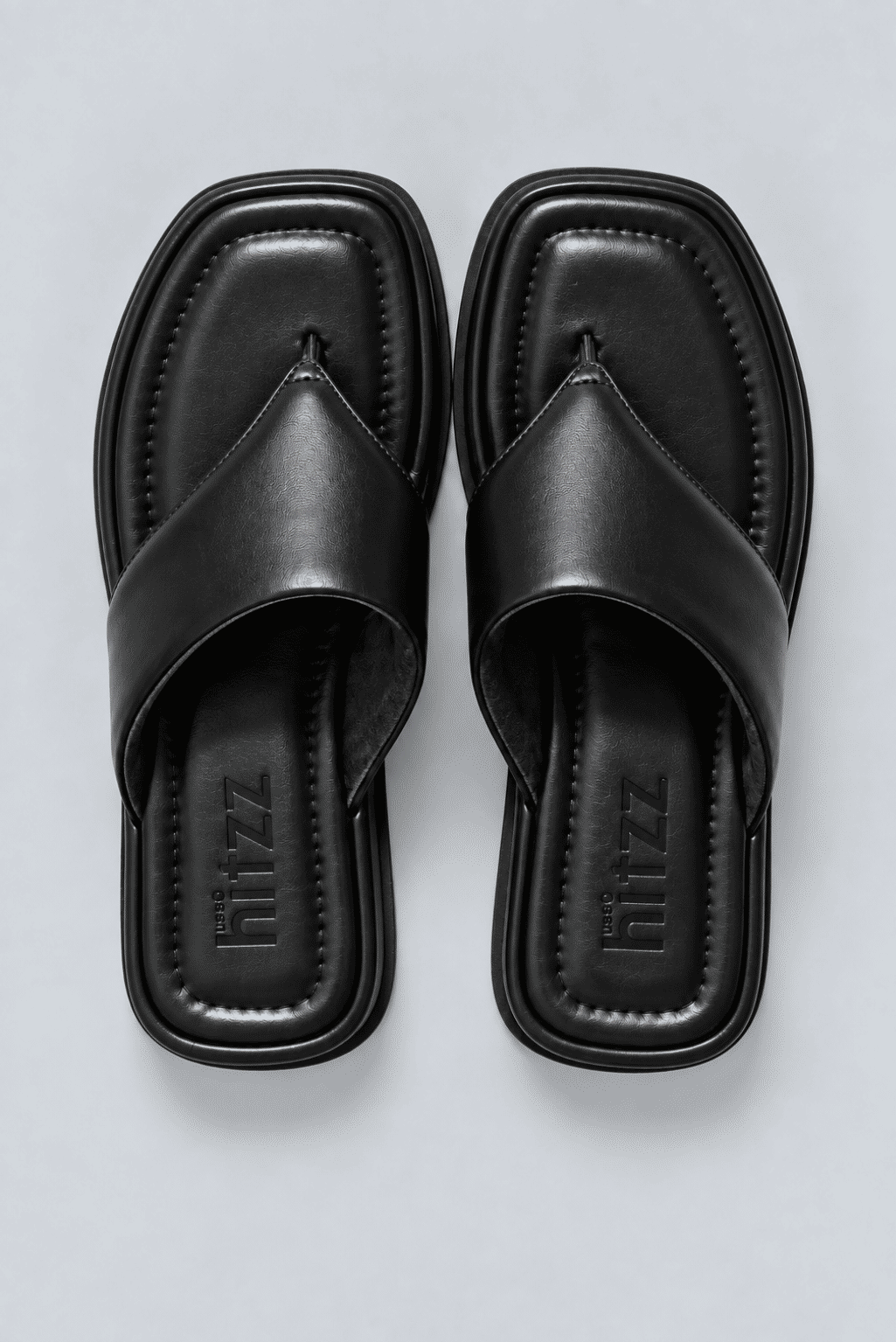 chinelo-flatform-couro-feminino-preto-buzios Par de chinelos flatform couro preto vistos de cima, palmilha com a marca hitzz gravada, fundo claro.