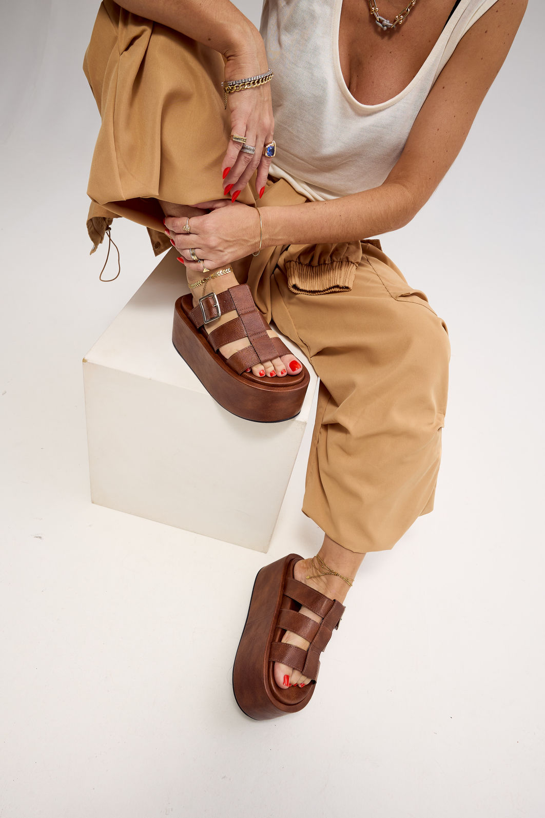 bangkok-tamanco-feminino-camel Modelo sentada em poltrona com calça bege e tamanco camel