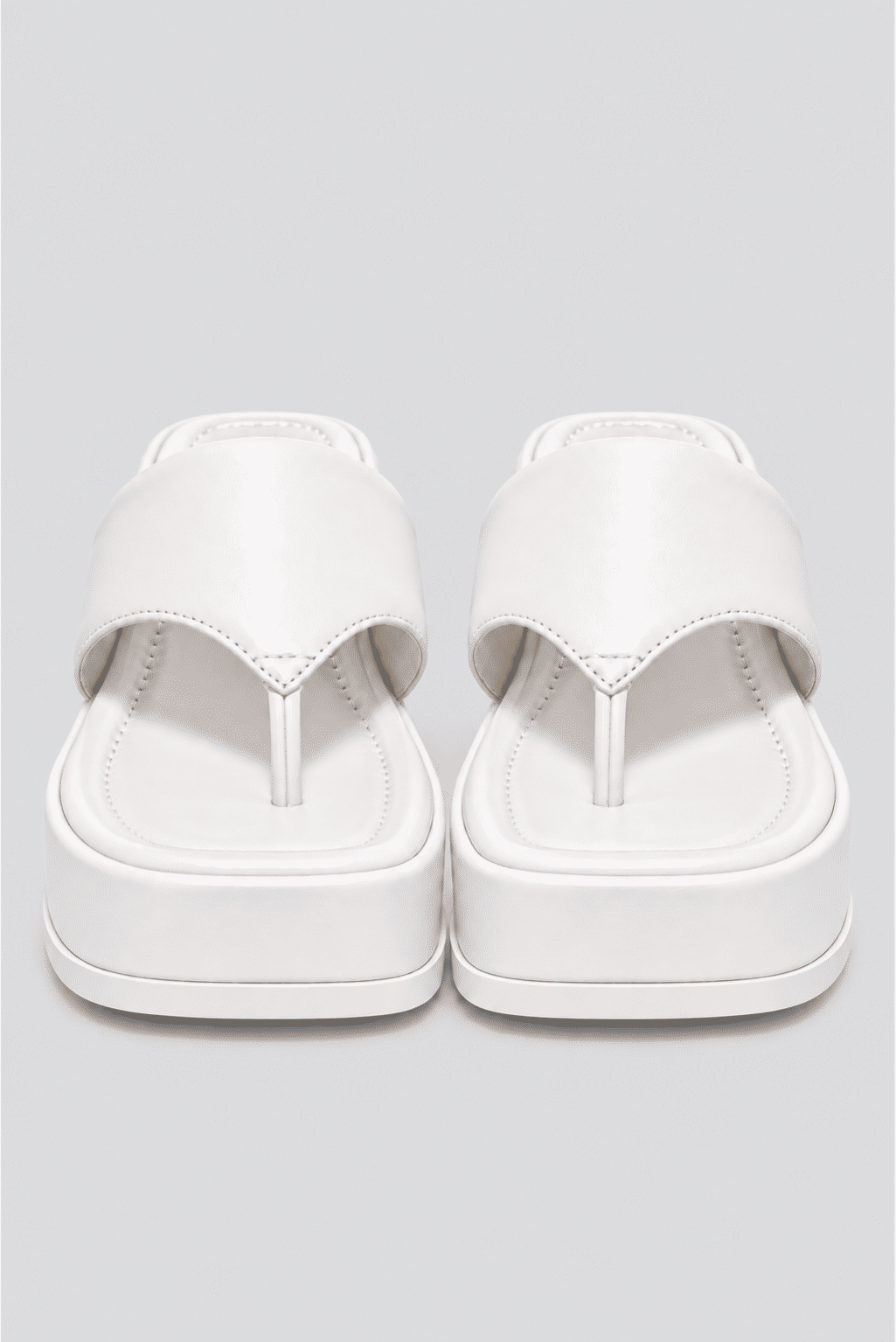 chinelo-flatform-couro-feminino-branco-buzios Par de chinelos flatform couro branco vistos de frente, mostrando a tira entre os dedos e o solado.
