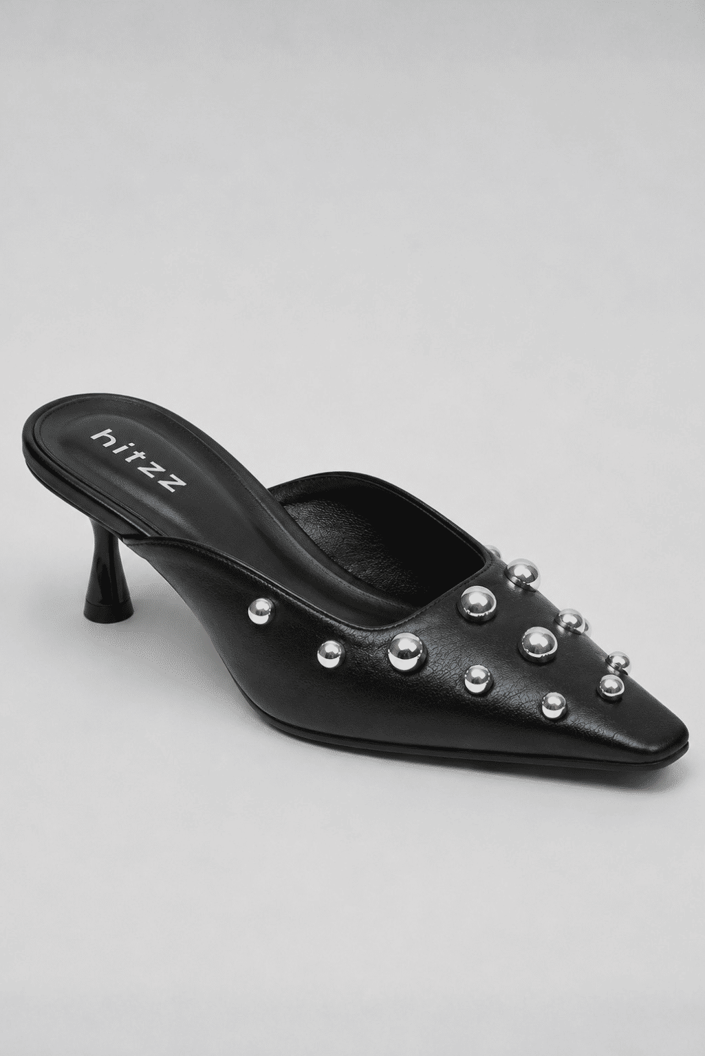 Mule Feminino Preto Zara com Aplicações Metálicas Mule feminino preto Zara em fundo claro, com bico fino, salto taça e aplicações metálicas esféricas prateadas distribuídas sobre o cabedal.