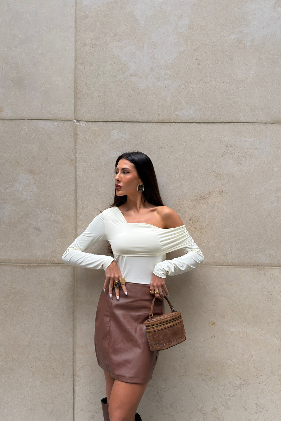 Saia feminina marrom em poliuretano com cintura alta e recortes verticais, modelagem ajustada e visual sofisticado tipo couro em look moderno com bota alta