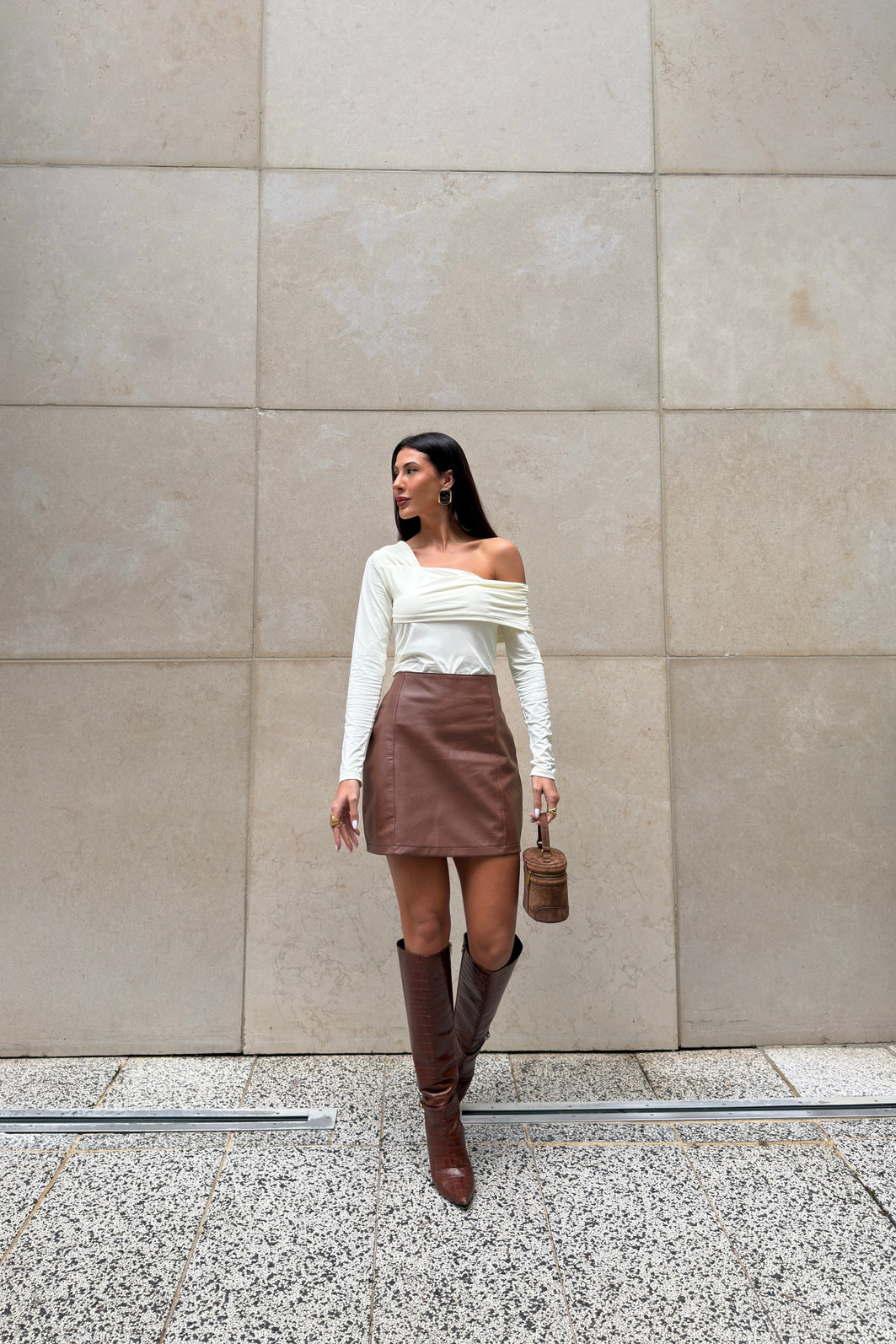 Saia feminina marrom em poliuretano com cintura alta e recortes verticais, modelagem ajustada e visual sofisticado tipo couro em look moderno com bota alta