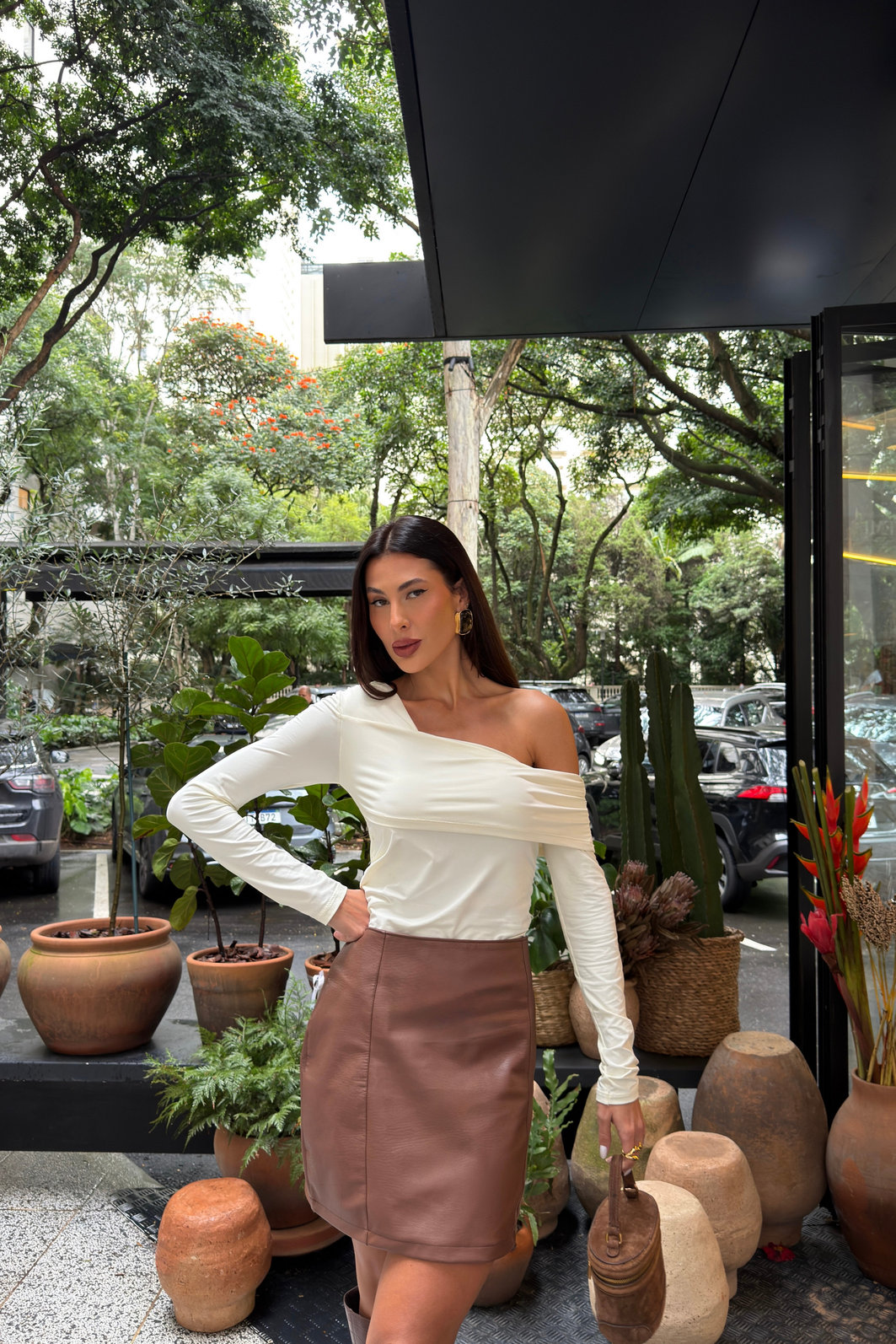 Saia feminina marrom em poliuretano com cintura alta e recortes verticais, modelagem ajustada e visual sofisticado tipo couro em look moderno com bota alta