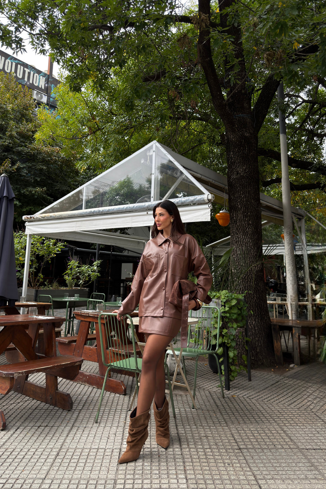 Saia feminina marrom em poliuretano com cintura alta e recortes verticais, modelagem ajustada e visual sofisticado tipo couro em look moderno com bota alta