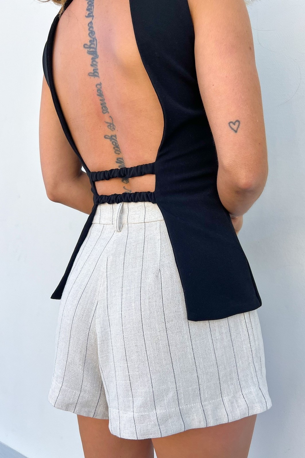 Detalhe das Costas Vazadas em Colete de Alfaiataria Close-up das costas do Colete Vivian, mostrando em detalhe os elásticos pretos que conectam as partes frontais da peça.