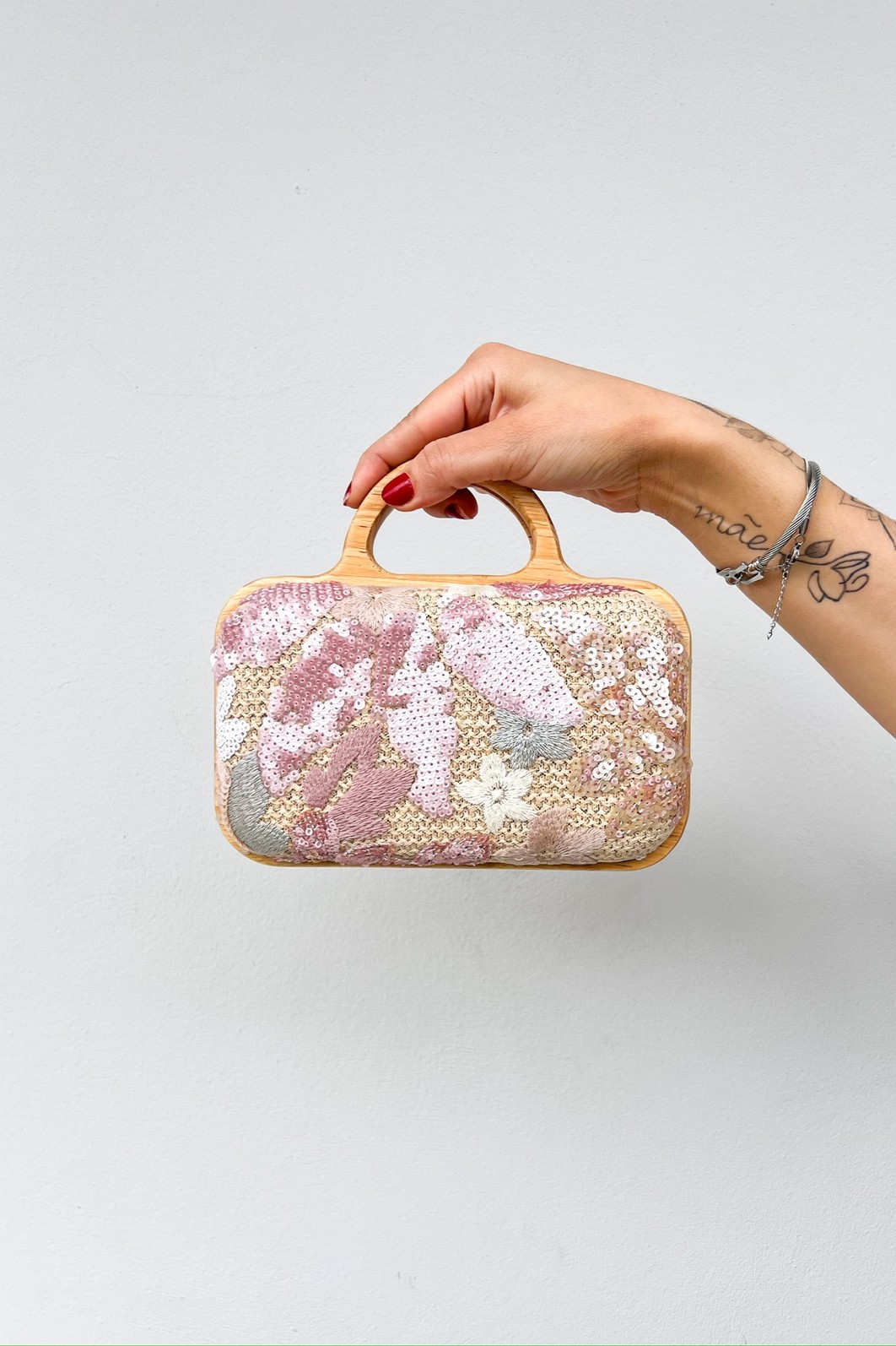 Bolsa Clutch Flora Rosê com estrutura de madeira, vista de frente para mostrar os detalhes do bordado misto de linha e paetês.