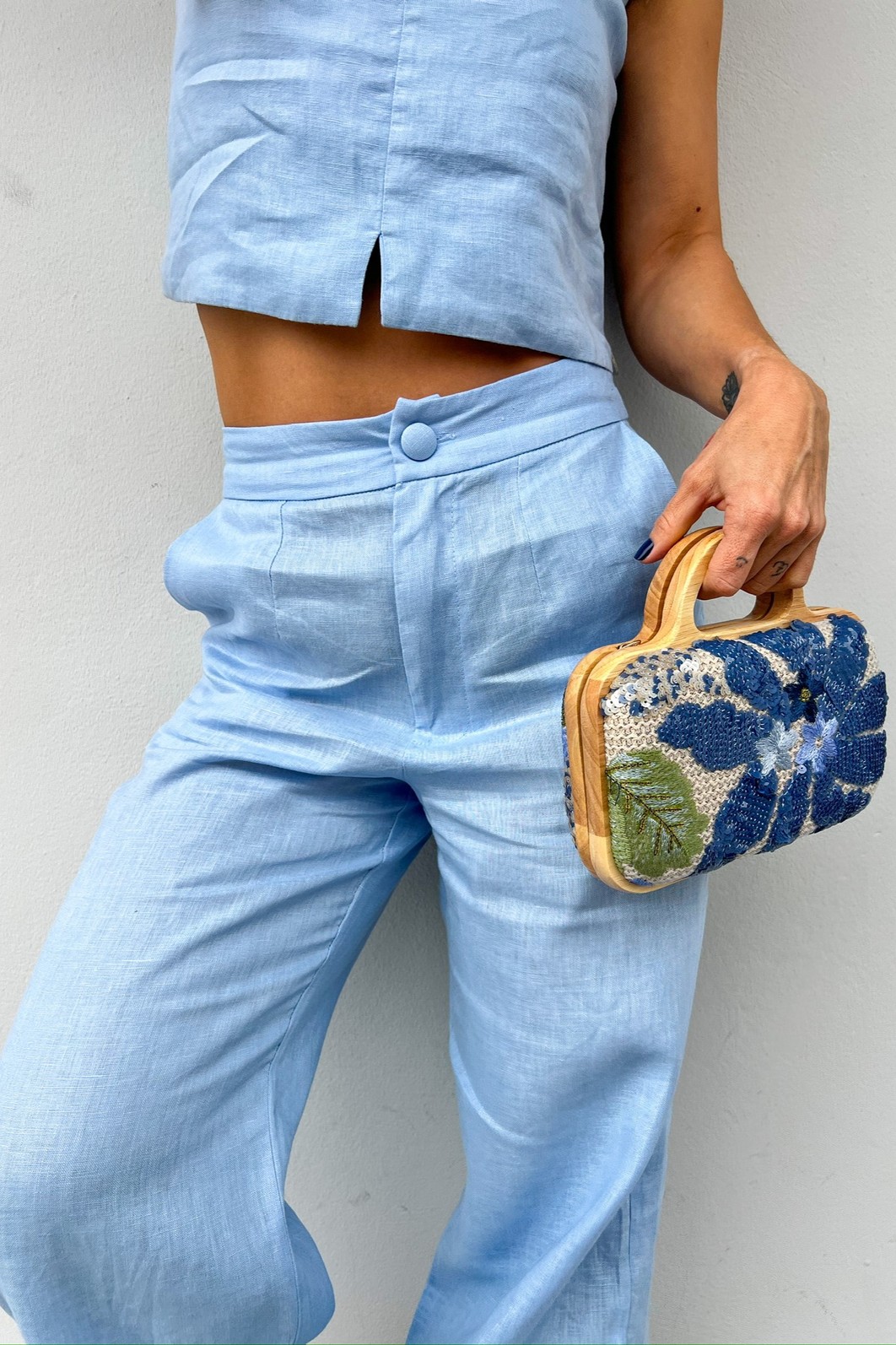 Close-up da lateral da Bolsa Clutch Flora, evidenciando a textura do tecido, o brilho dos paetês e a estrutura de madeira natural.