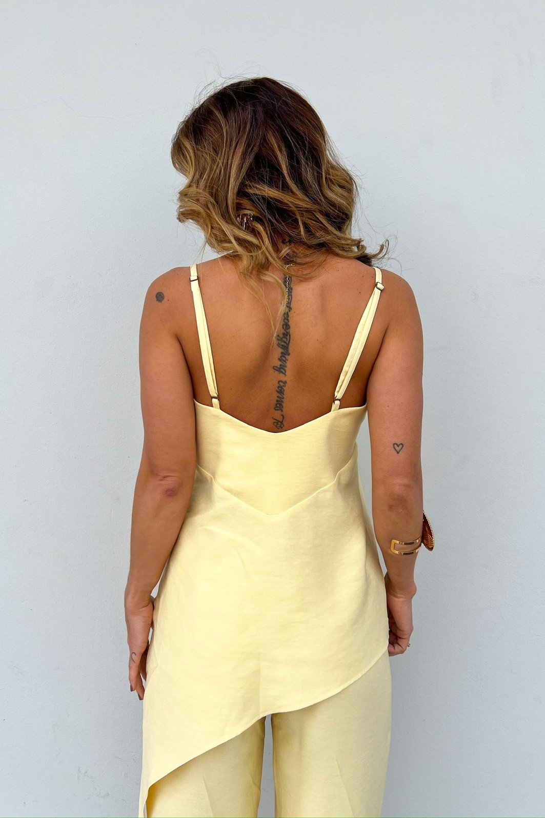 Detalhe da Fenda em Blusa de Alça Amarela de Viscose Close-up da lateral da Blusa Eleonora, mostrando o movimento e a fluidez criados pela ponta com fenda no tecido de viscose