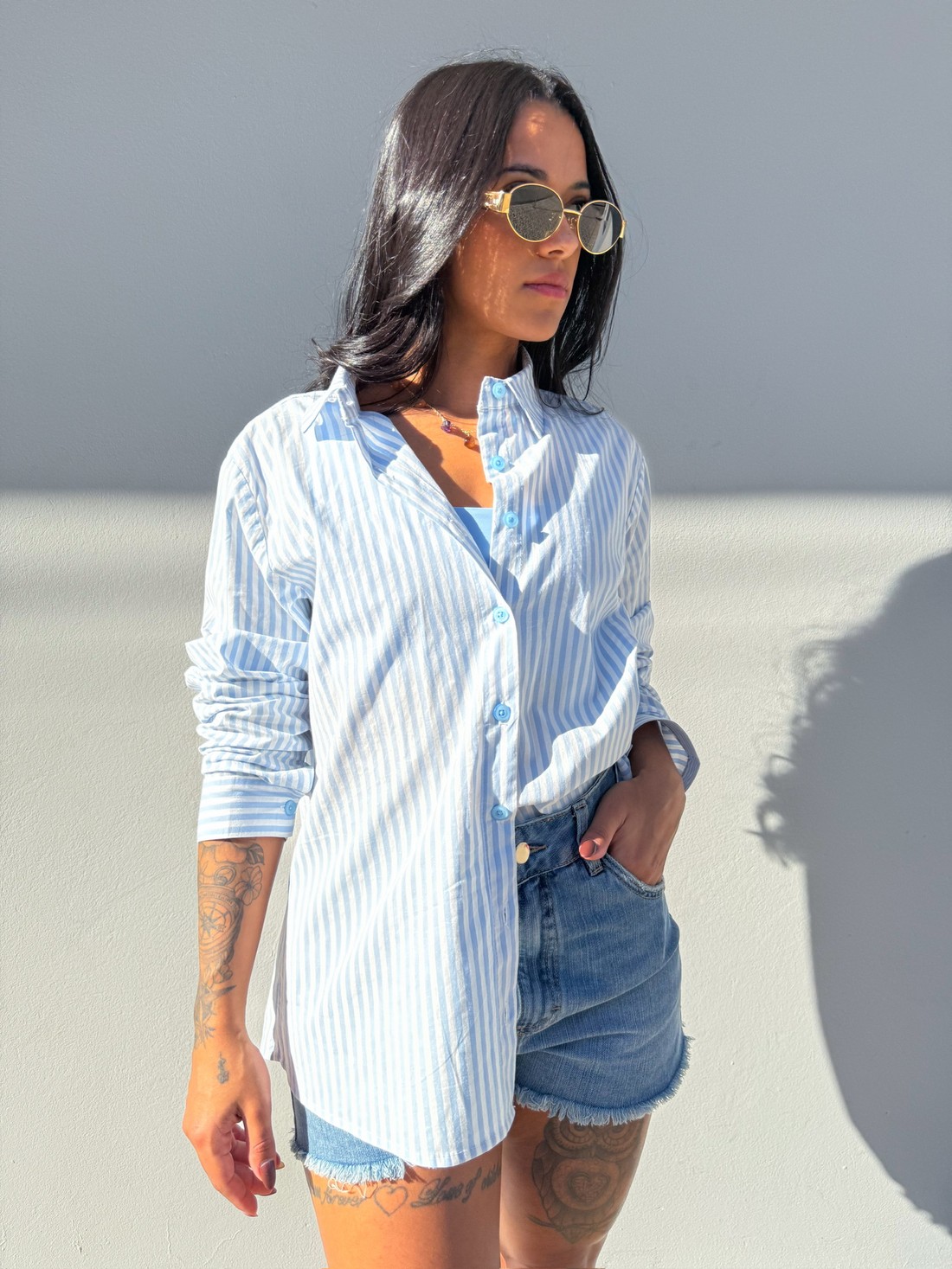 camisa listrada azul feminina, camisa leve verão, short jeans desfiado, moda casual feminina, look confortável, tendência feminina, camisa longa com short, outfit casual, camisa azul clara, estilo jovem feminino