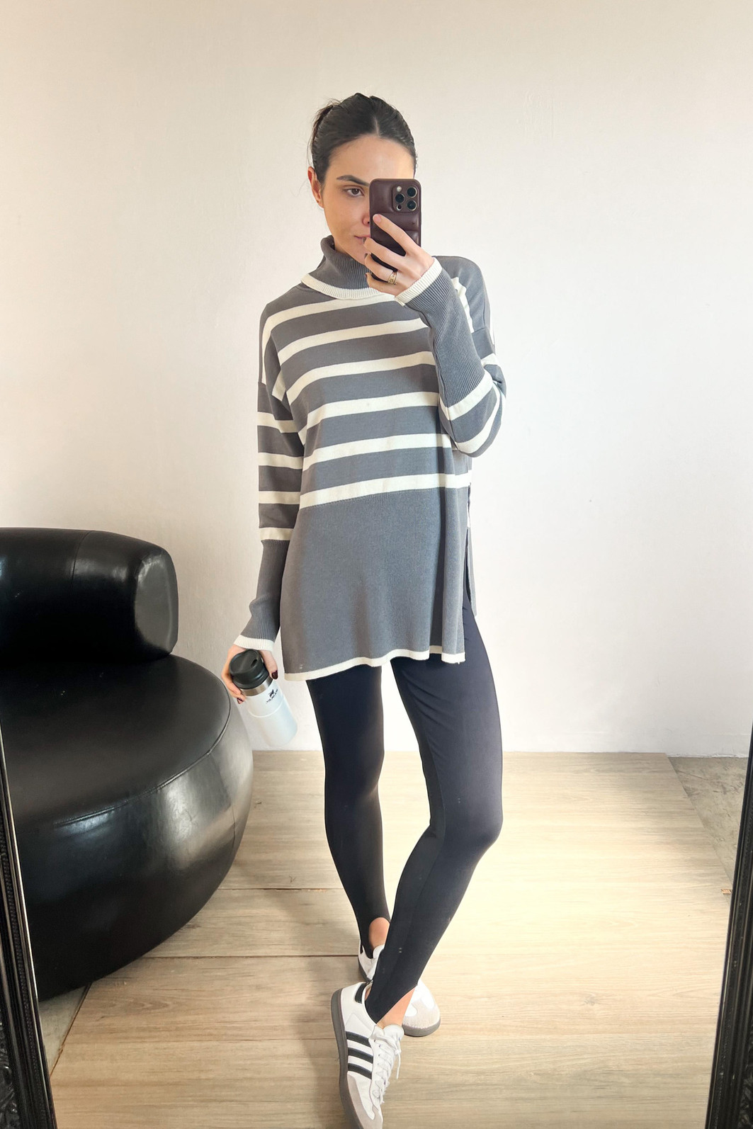 modelo em frente ao espelho usando blusão cinza de manga longa e gola alta com legging fusô preta