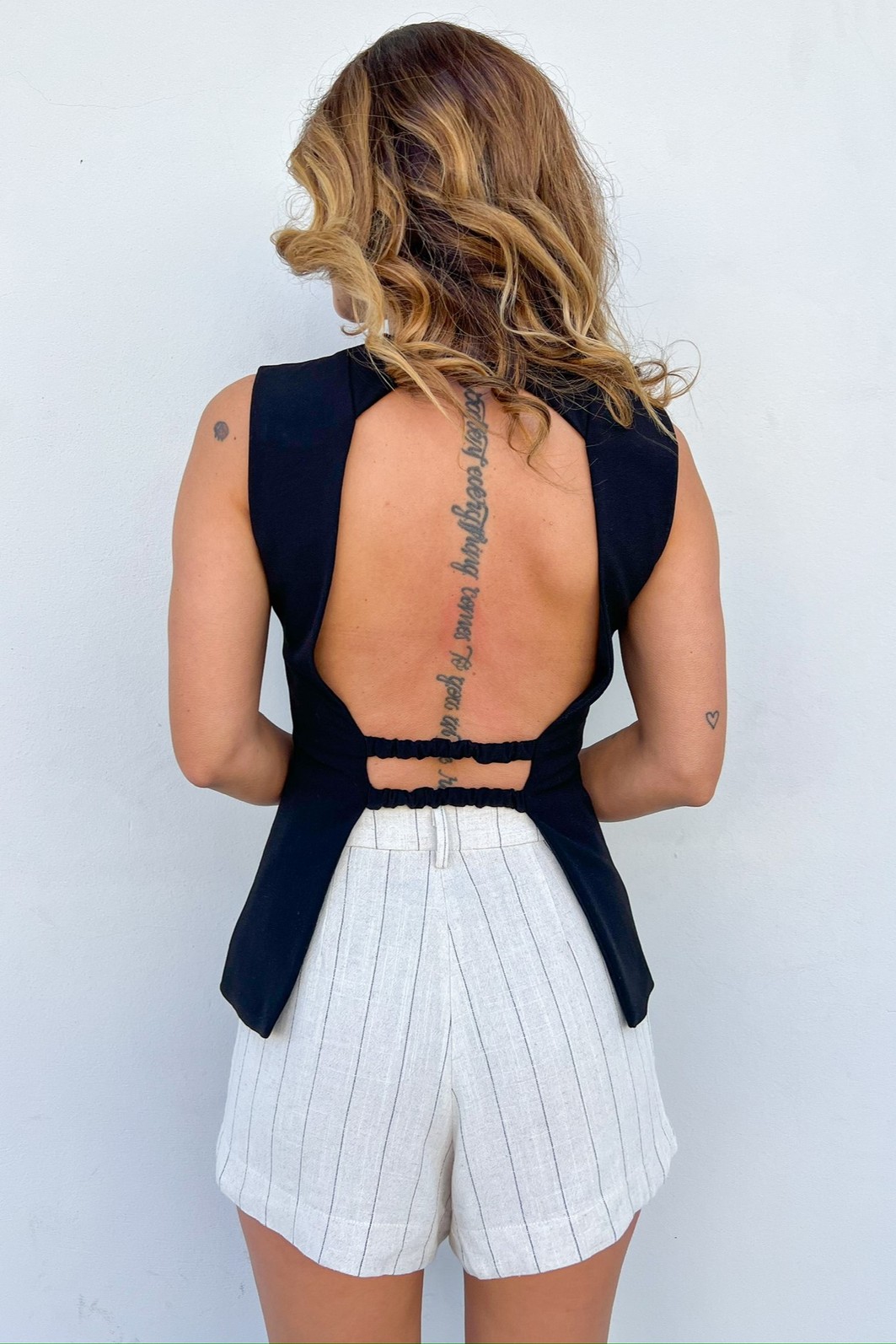 Colete com Costas Abertas e Elásticos de Ajuste ista de costas do Colete Vivian, destacando o design inovador com a parte de trás totalmente aberta e os elásticos de ajuste na cintura.