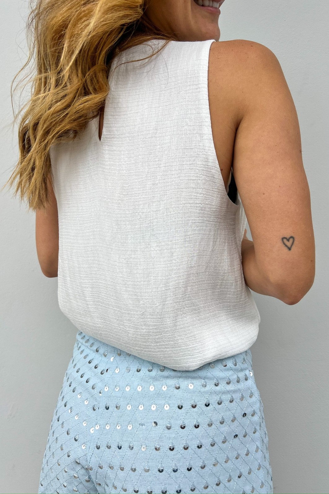 Vista de costas da Blusa Branca Off Teodora, mostrando o fechamento com o delicado botão perolado na nuca e o corte elegante sem mangas.