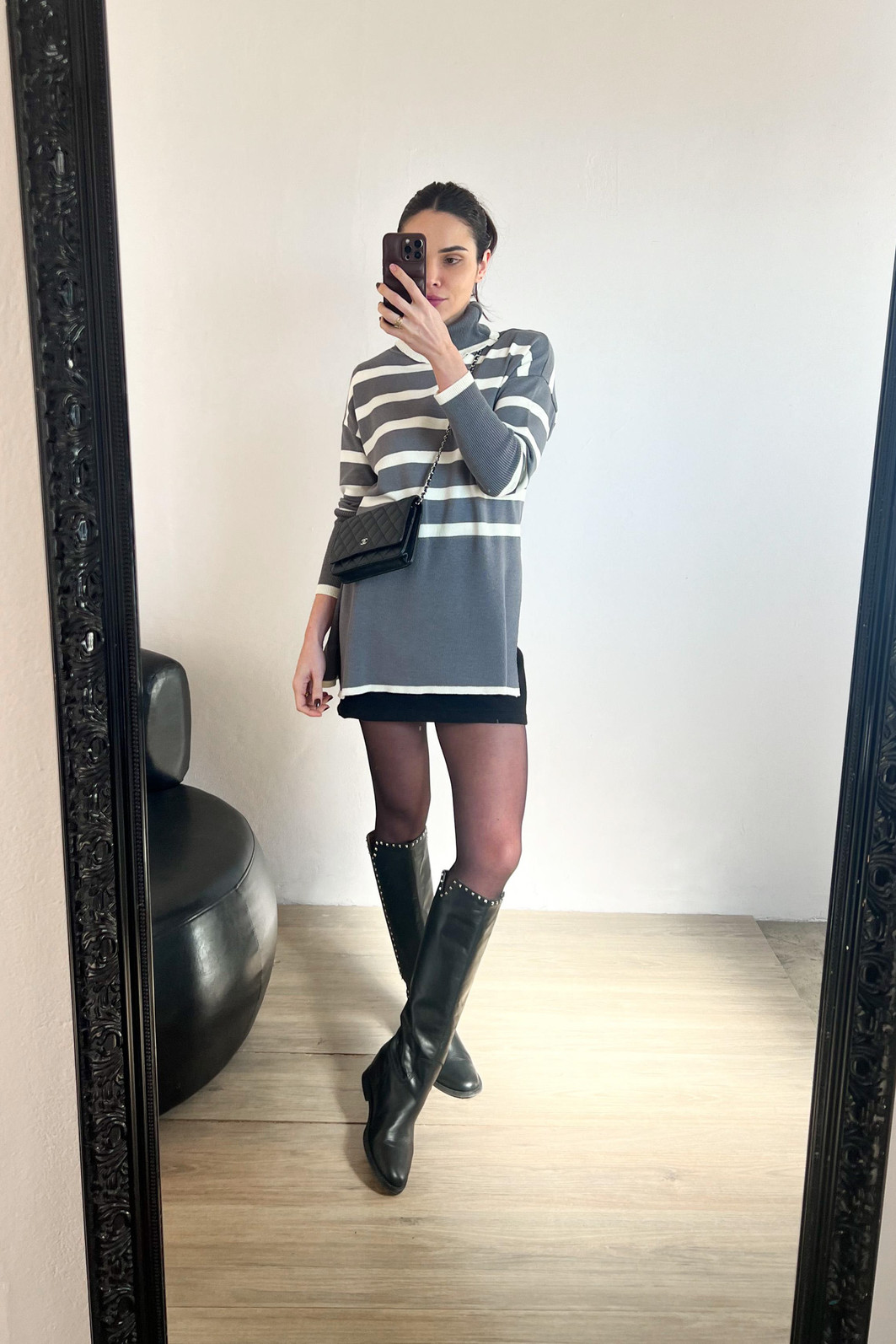 modelo em frente ao espelho usando blusao de manga longa e gola alta listrado com saia e meia calça preta