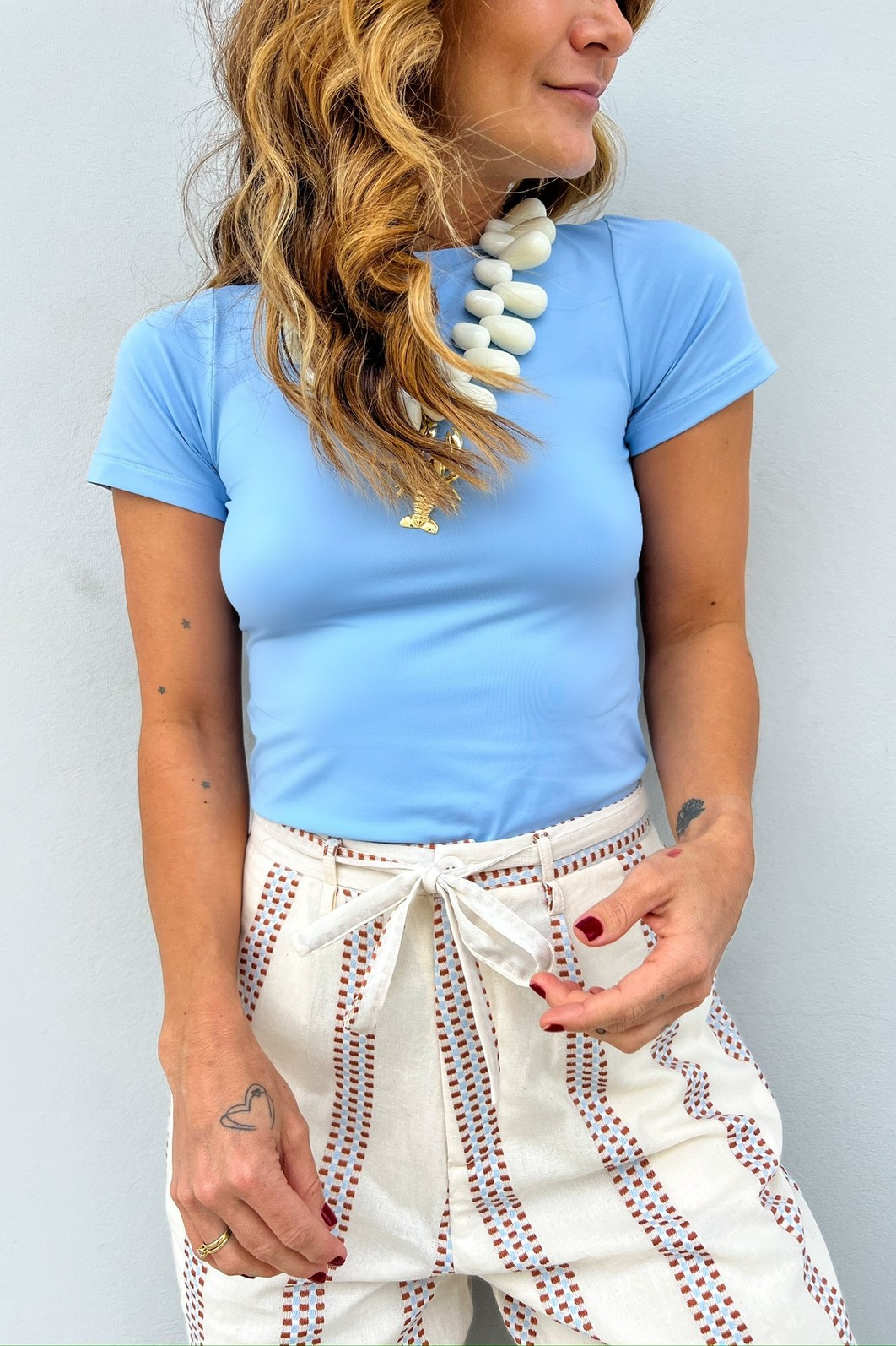 Look casual chic com a Blusa Fit Azul Céu combinada com uma calça de linho branca, criando um visual fresco e elegante.