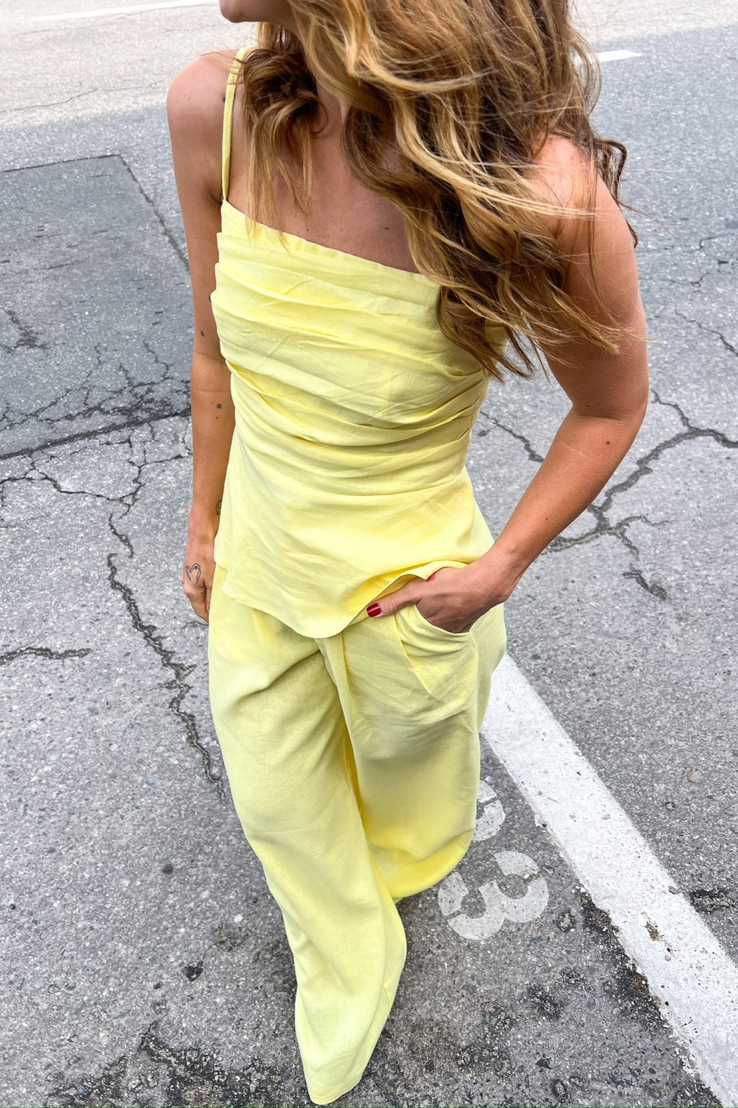 Calça de Alfaiataria Feminina Reta em Linho Amarelo Modelo vestindo a Calça de Linho Amarela Eveline, mostrando o corte reto de alfaiataria e a cor solar do tecido.