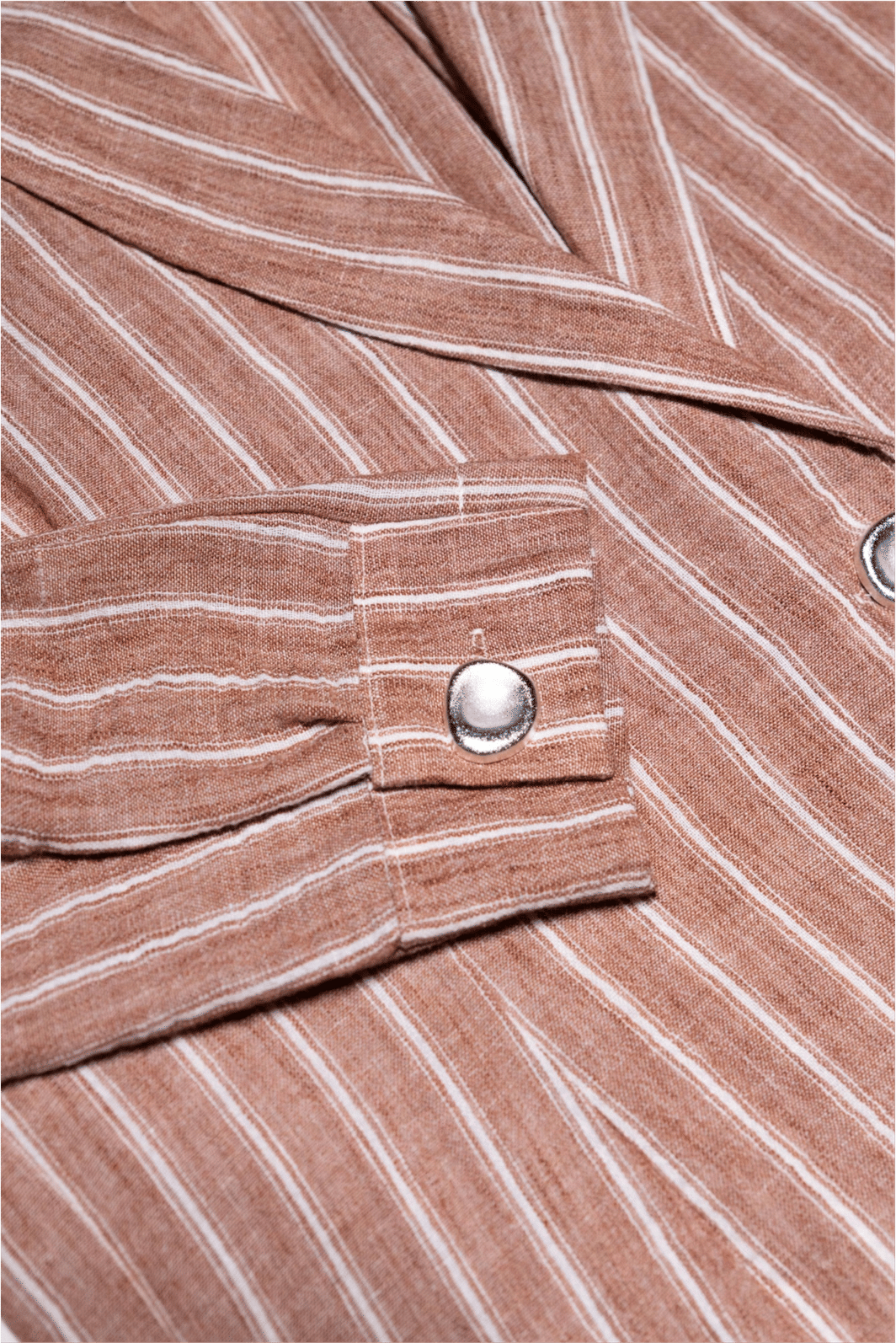 Close-up do punho do Blazer Camisa de Listras Abby, destacando o design único e o brilho do botão prateado sobre o tecido listrado.