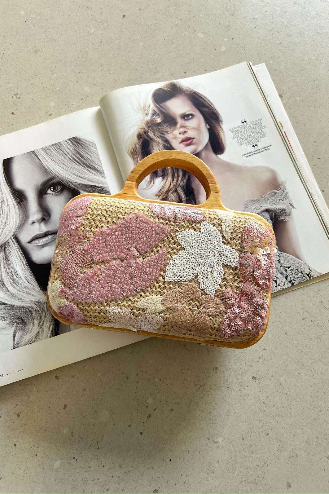 Clutch Rosê com Bordado de Paetês e Alça de Corrente Clutch Flora Rosê com as duas opções de alça: a de mão em madeira e a alça longa de corrente dourada ao lado, mostrando sua versatilidade.