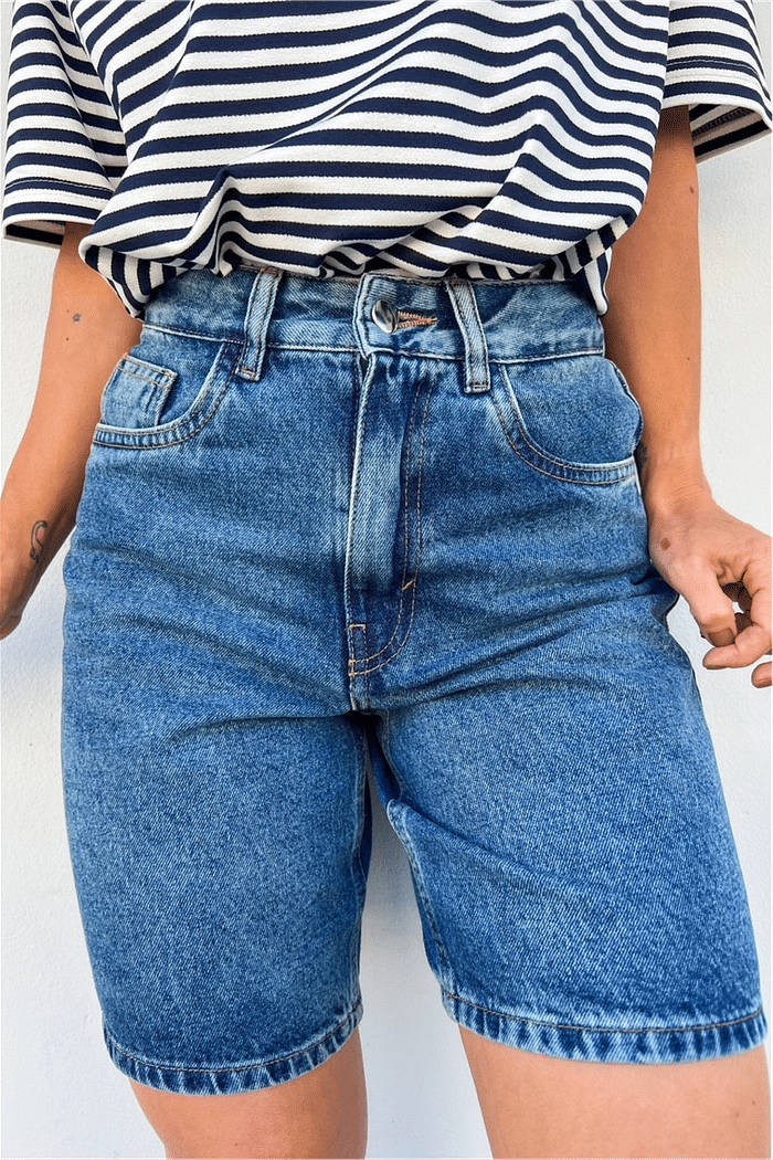 Look Elegante com Bermuda Jeans Mom Escura Look completo com a Bermuda Jeans Mom Lia combinada com uma blusa de listras, criando um visual clássico e elegante.