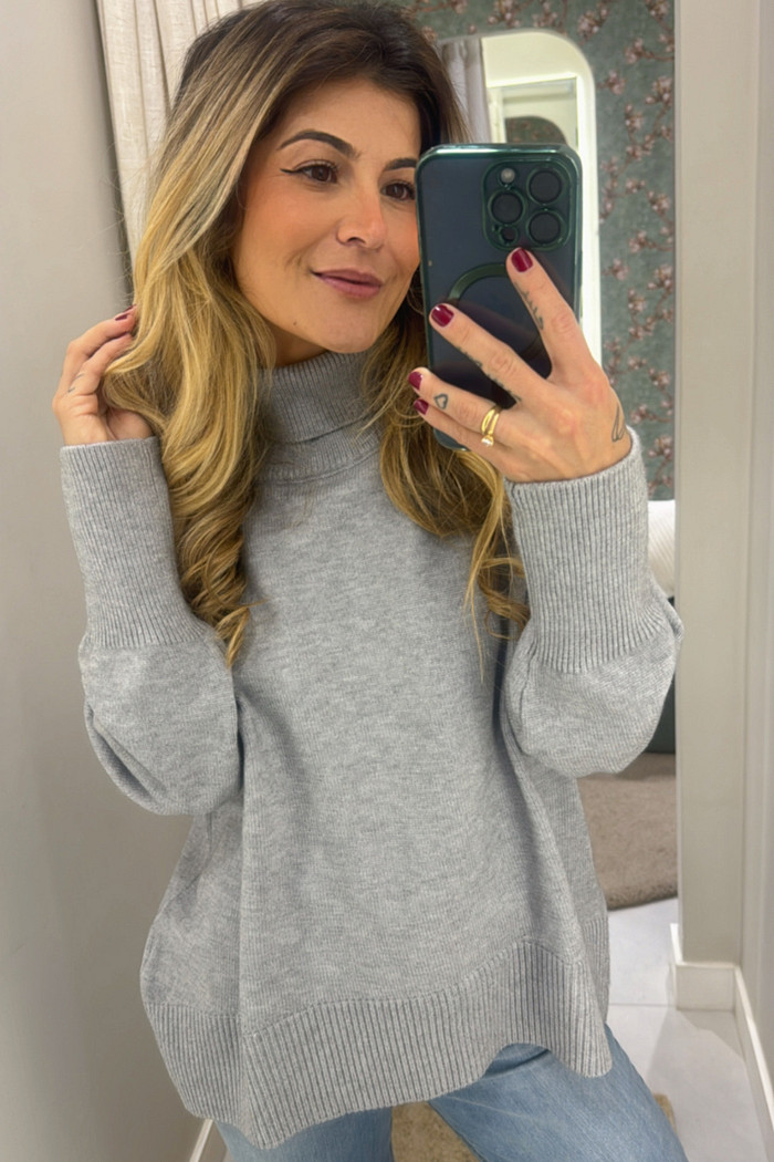 modelo em frente ao espelho usando produto tricô de gola alta cinza 