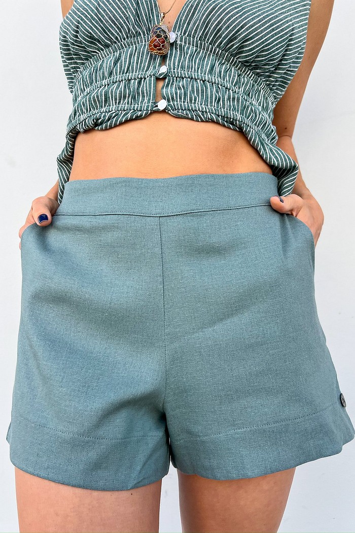 Shorts verde feminino de alfaiataria leve – MiniMoni Shorts de alfaiataria verde feminino MiniMoni em linho e viscose, com botão forrado e modelagem reta, peça leve e elegante para trabalho e lazer.