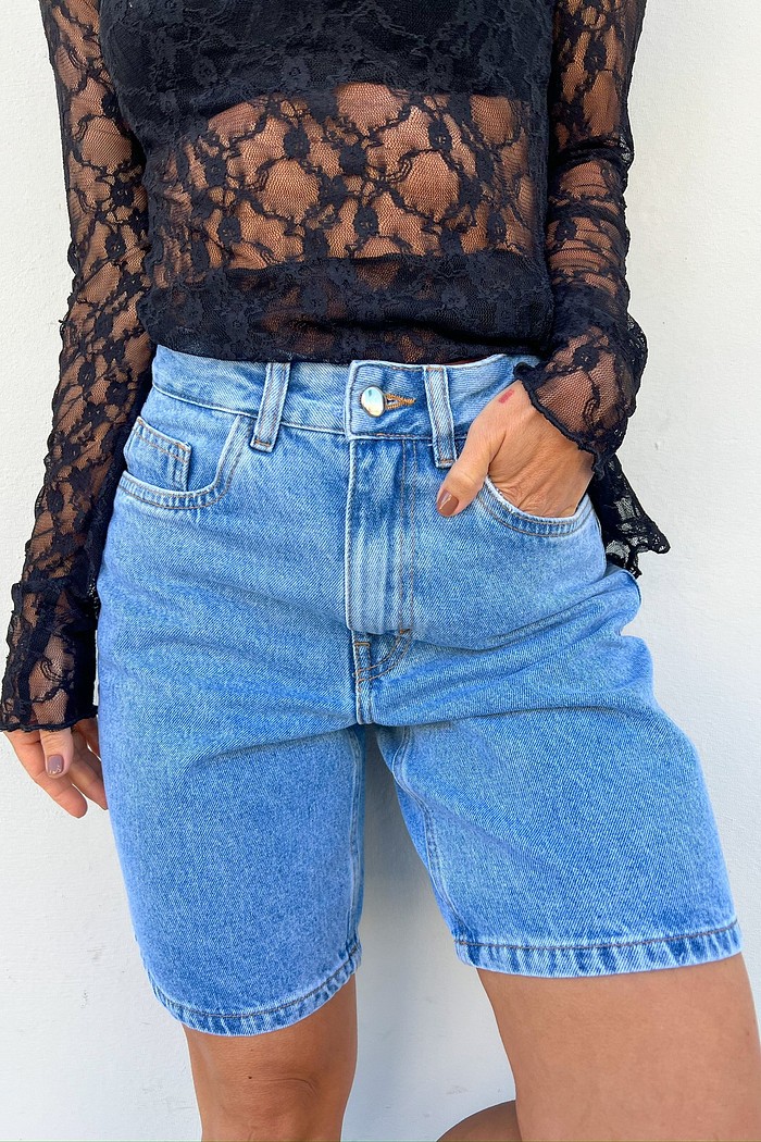 Bermuda Jeans Feminina Estilo Mom com Lavagem Clara Modelo vestindo a Bermuda Jeans Mom Lia na cor light blue, mostrando a cintura alta e o comprimento mais alongado da peça.