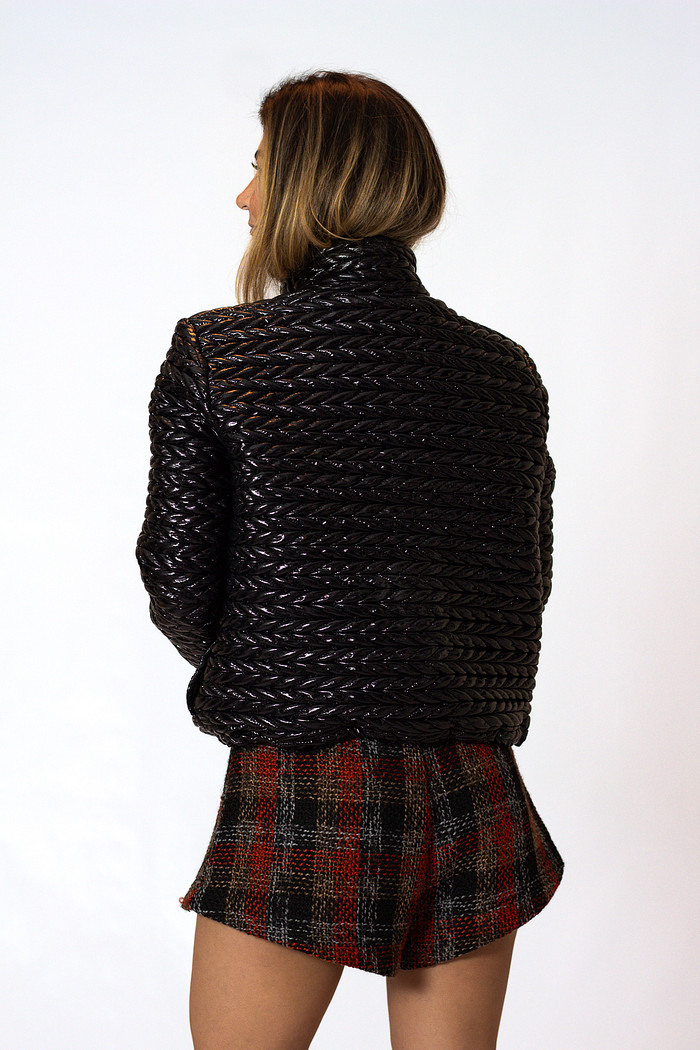 Modelo vestindo jaqueta puffer preta feminina e shorts xadrez de alfaiataria