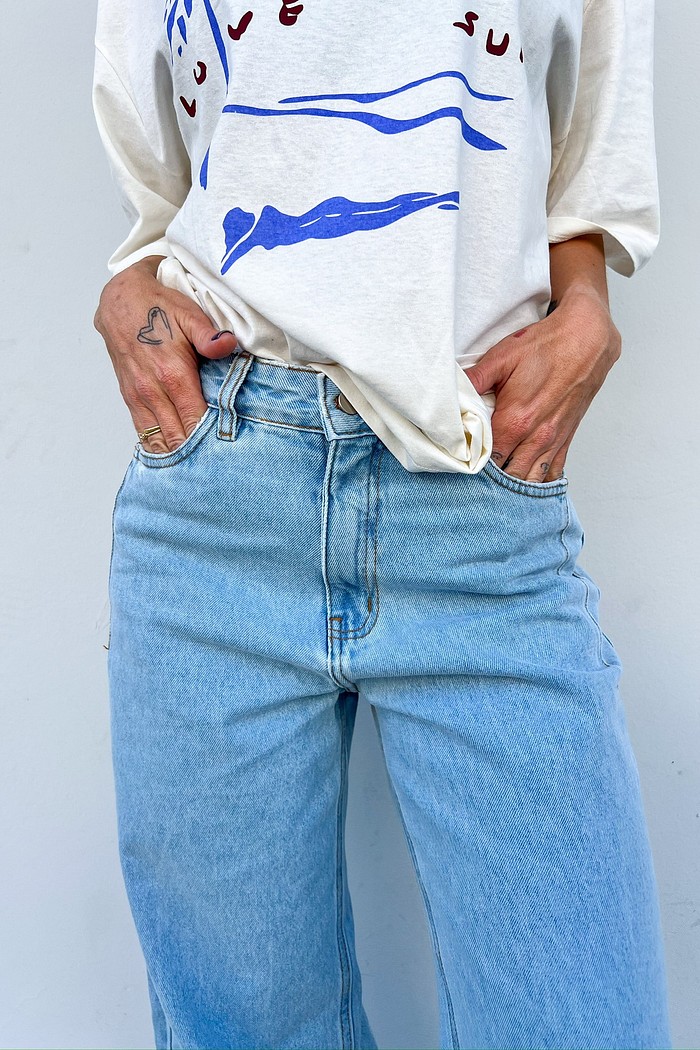 Calça Jeans de Corte Reto 100% Algodão - MiniMoni Modelo em pose descontraída usando a Calça Jeans Wide Leg Vicky, demonstrando a fluidez e o conforto do corte reto ao caminhar.