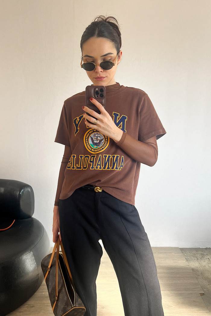 modelo utilizando blusa de manga curta marrom sobreposta a uma blusa de tule e calça de alfaiataria preta