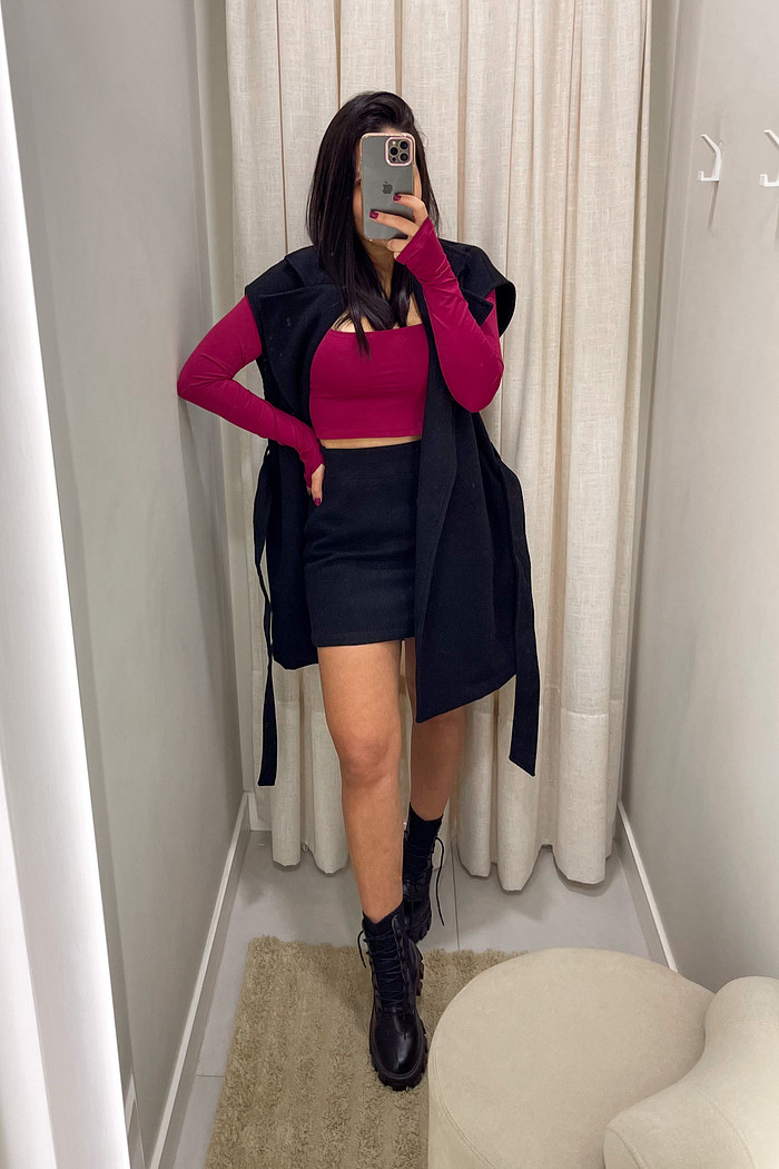 blusa cropped vermelho cereja manga longa bettina-1 modelo em frente ao espelho usando cropped vermelho cereja com mini saia de lã batida preta e maxi colete de lã batida preto por cima