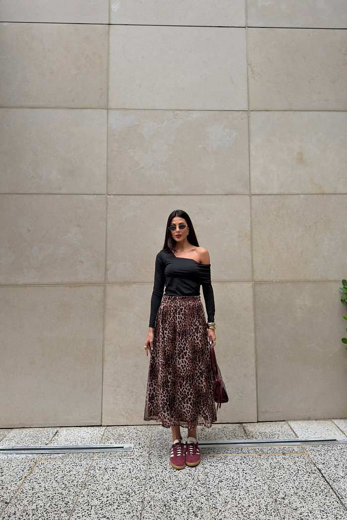 Blusa preta com decote assimétrico, drapeado caindo no ombro e mangas longas franzidas.