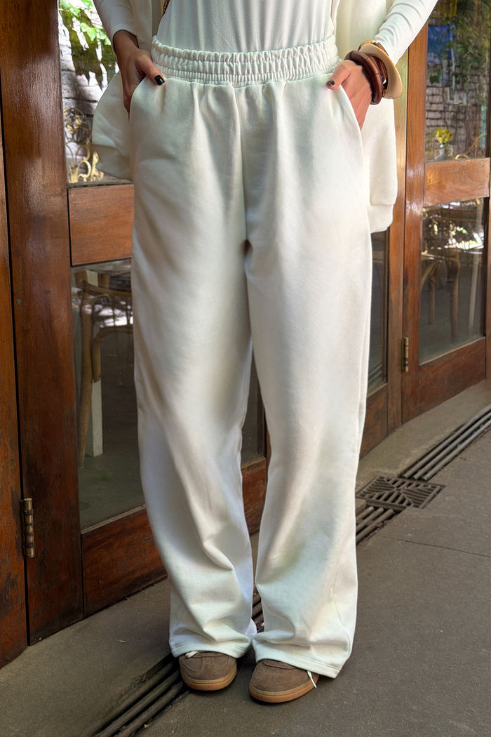 Calça wide leg off white em moletom felpado, cintura com elástico embutido e bolsos frontais, modelo feminino