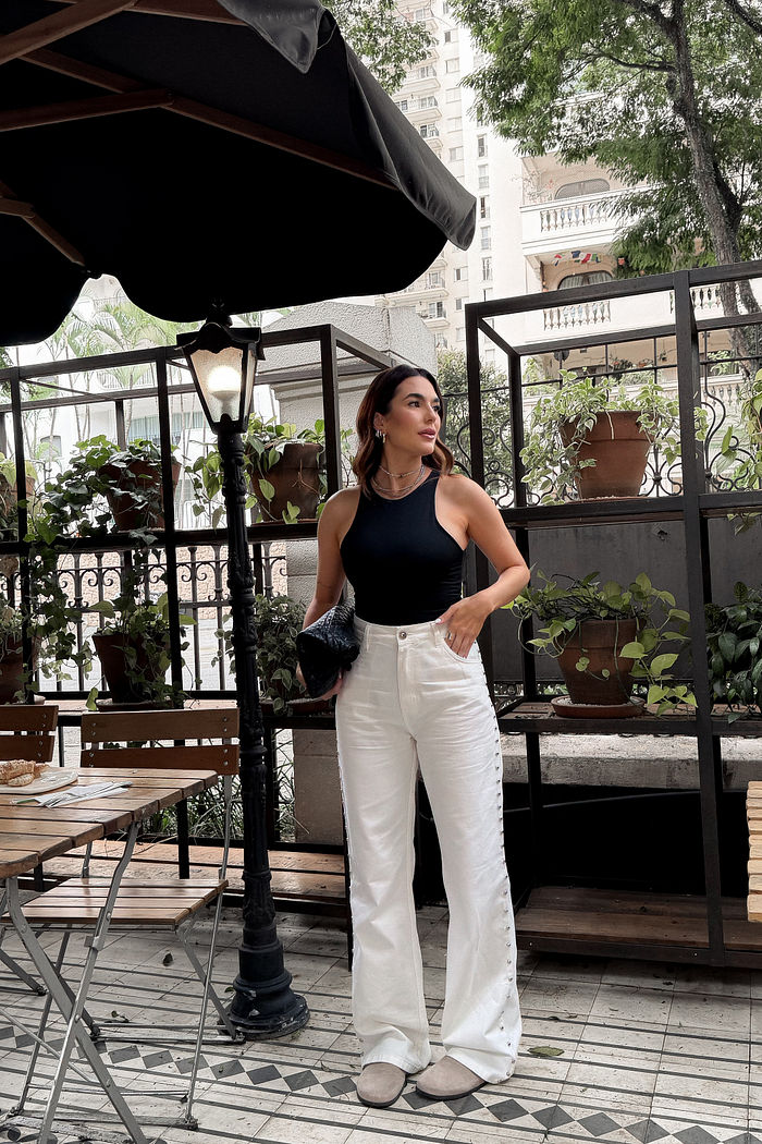 Calça wide leg off white em sarja com taxas prateadas aplicadas na lateral e cintura alta.